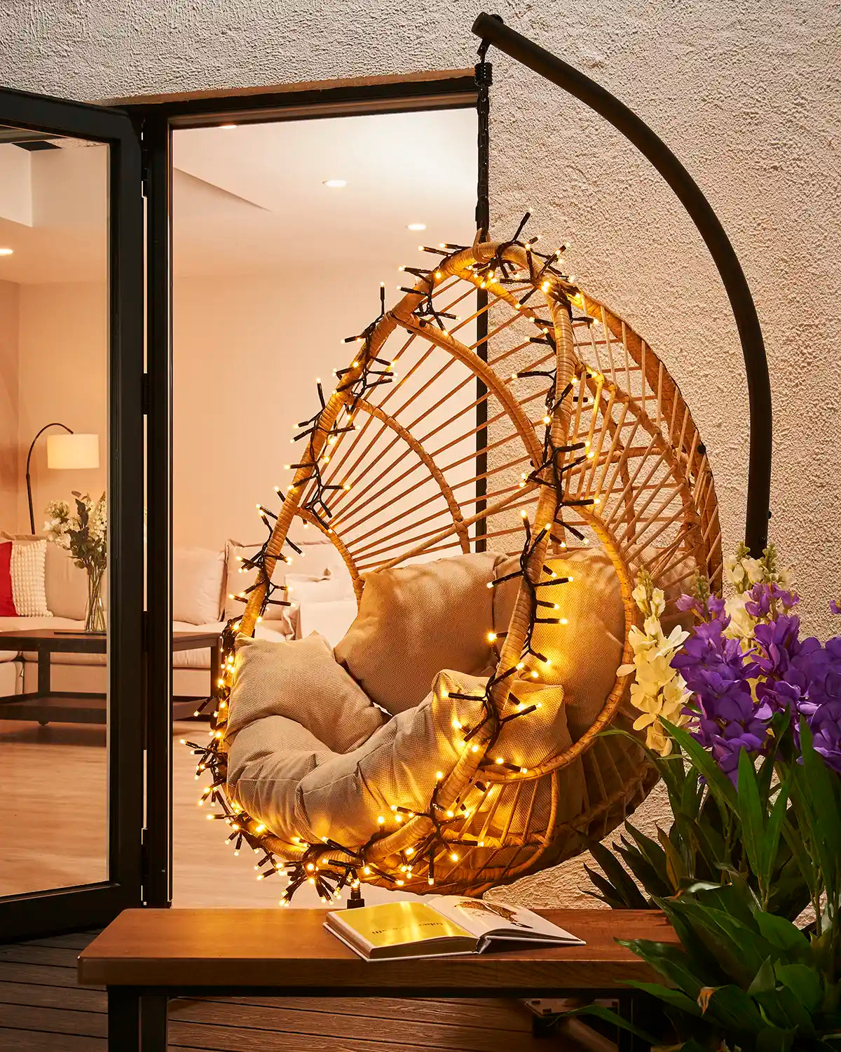 Warm white cluster lights wrapped around an outdoor hanging chair.