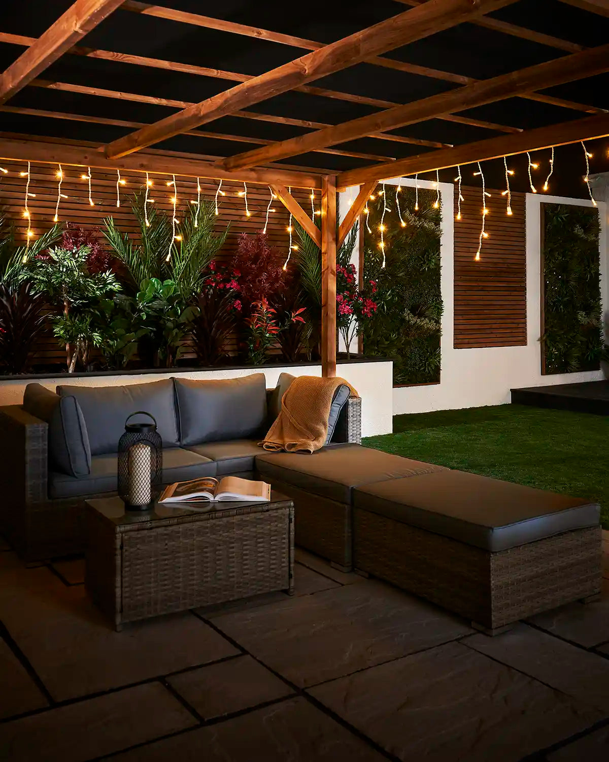 Warm white icicle lights displayed above an outdoor seating area under a pergola.