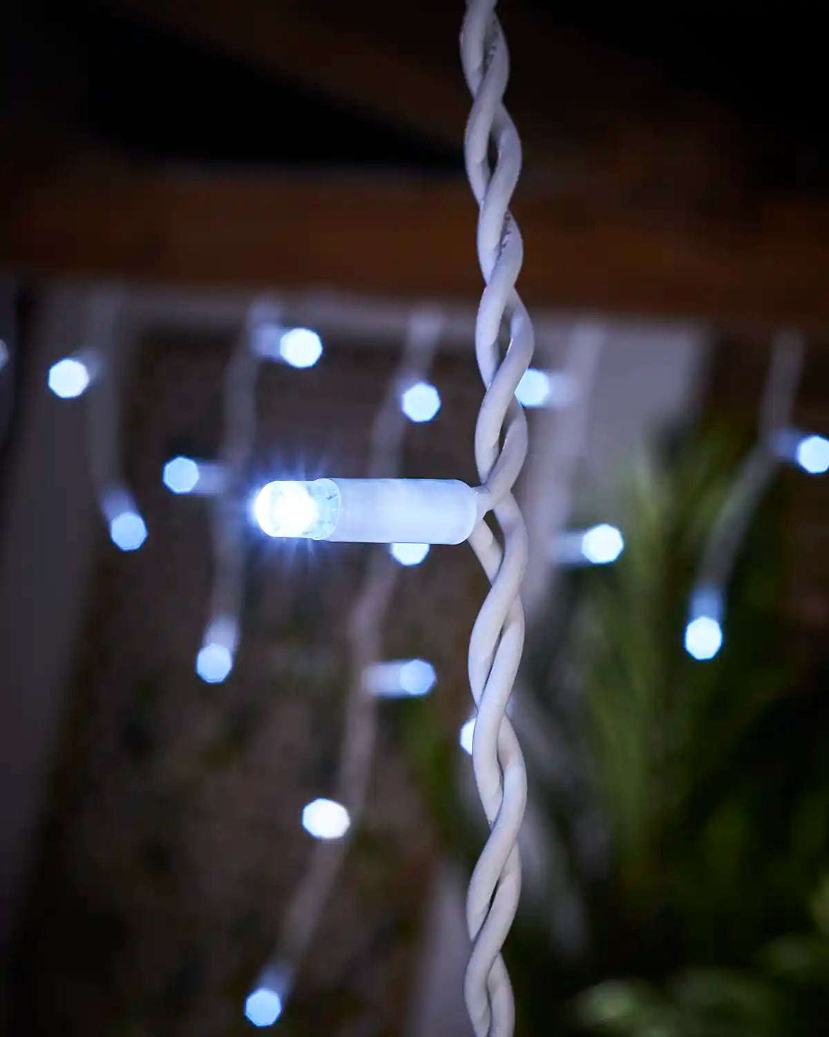 Close-up of a white LED icicle light on white twisted cable.