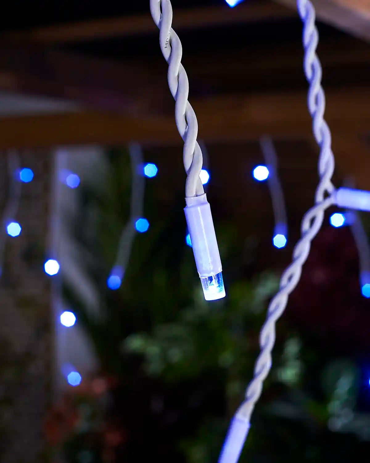 Close-up of a blue LED icicle light on white twisted cable.
