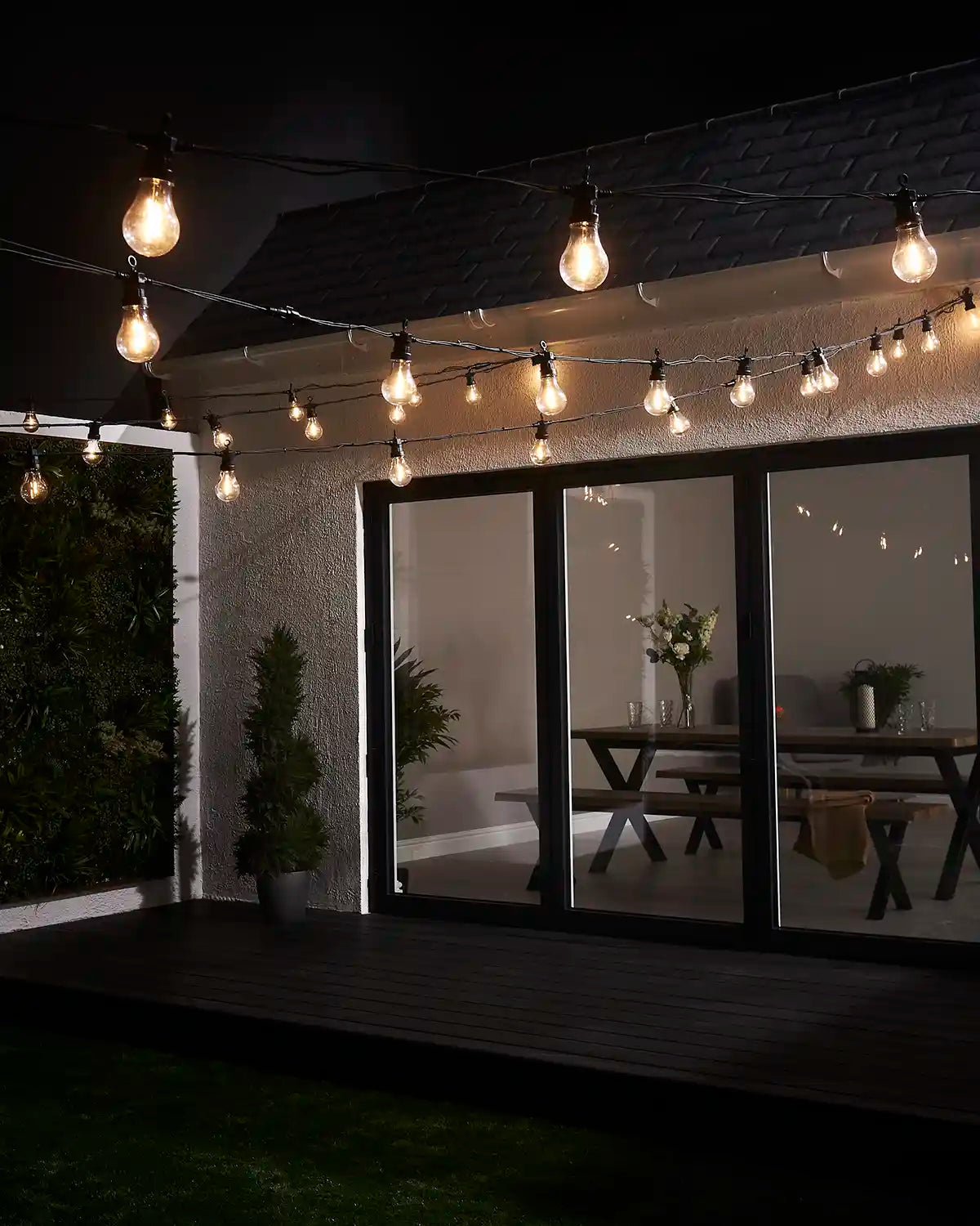 A60 filament festoon lights displayed across a garden patio and house exterior.