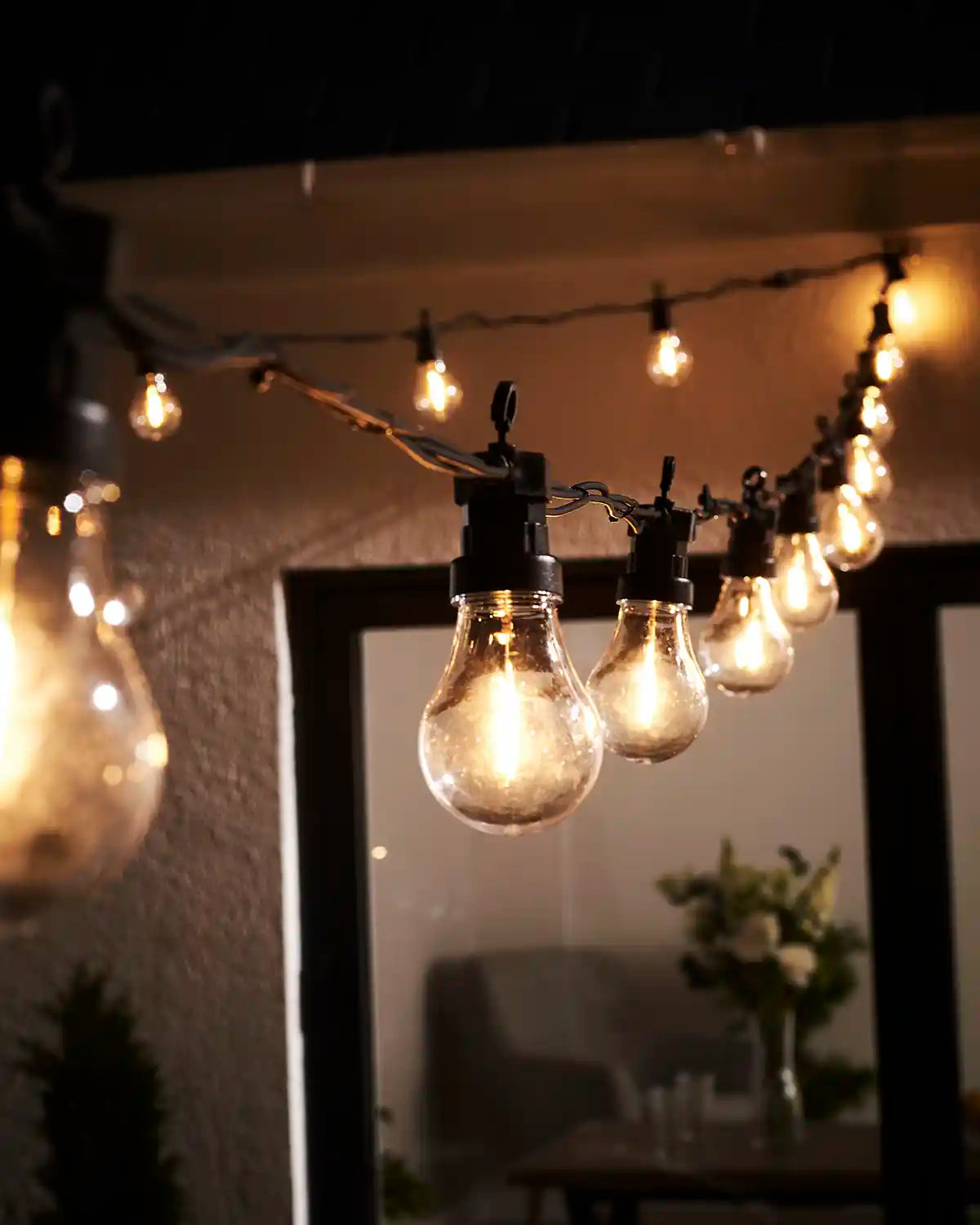 Warm white A60 filament festoon bulbs hanging above an outdoor patio.