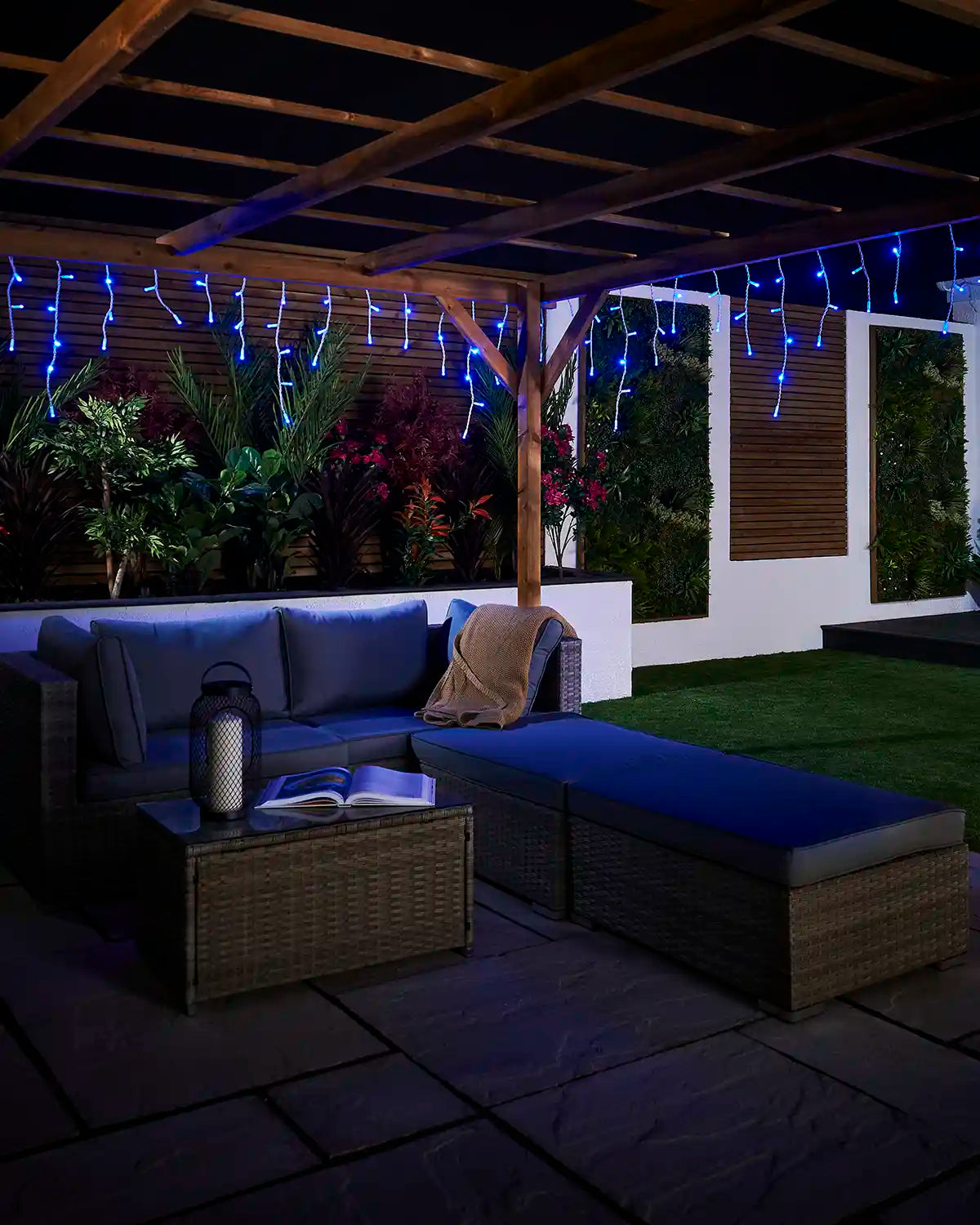 Blue icicle lights displayed above an outdoor seating area under a pergola.