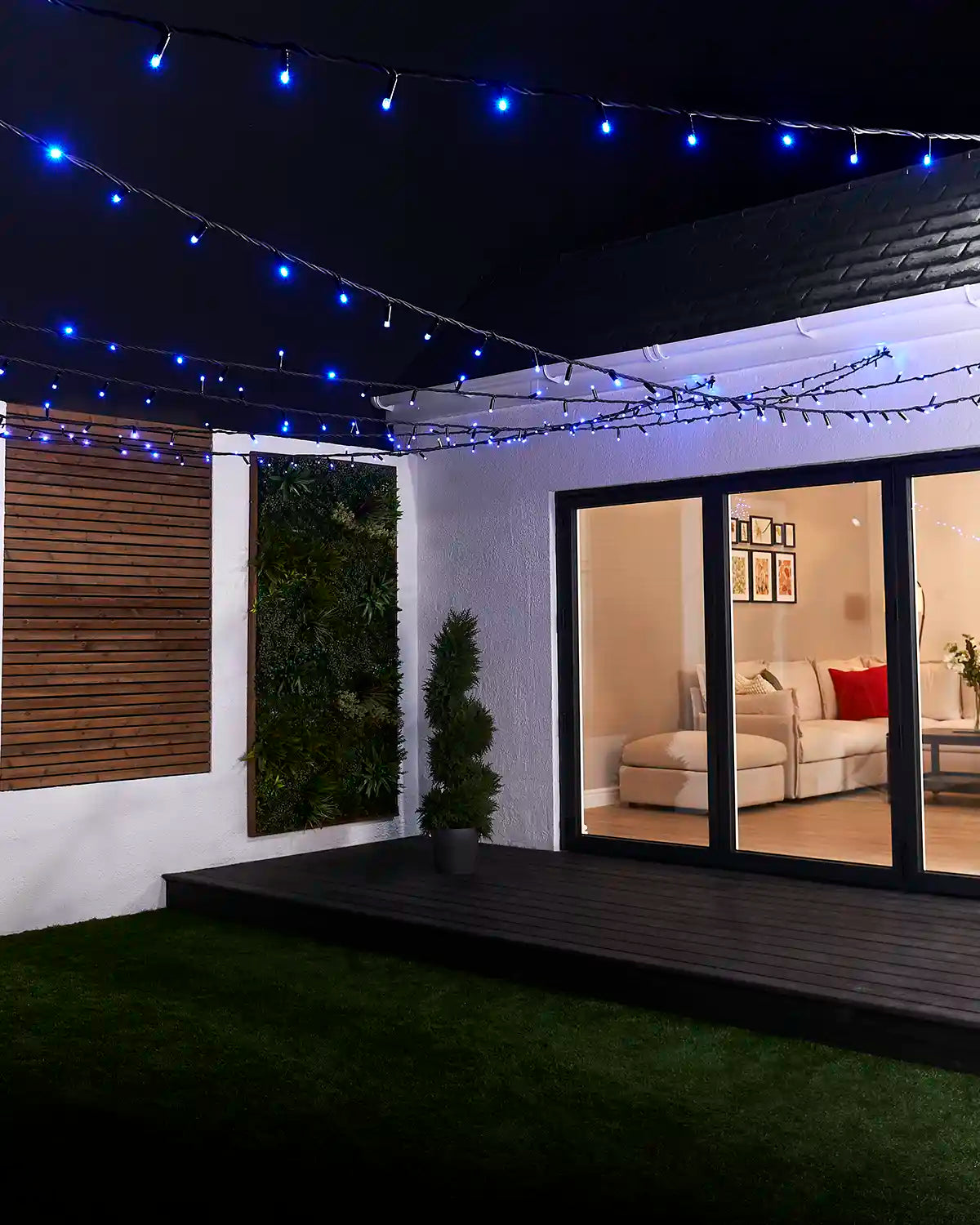 Blue LED string lights suspended across an outdoor garden seating area.