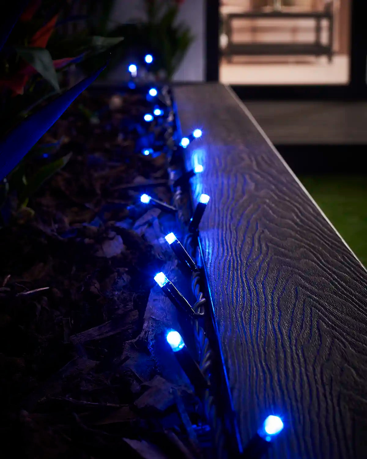 Blue LED string lights displayed along the edge of an outdoor planter.