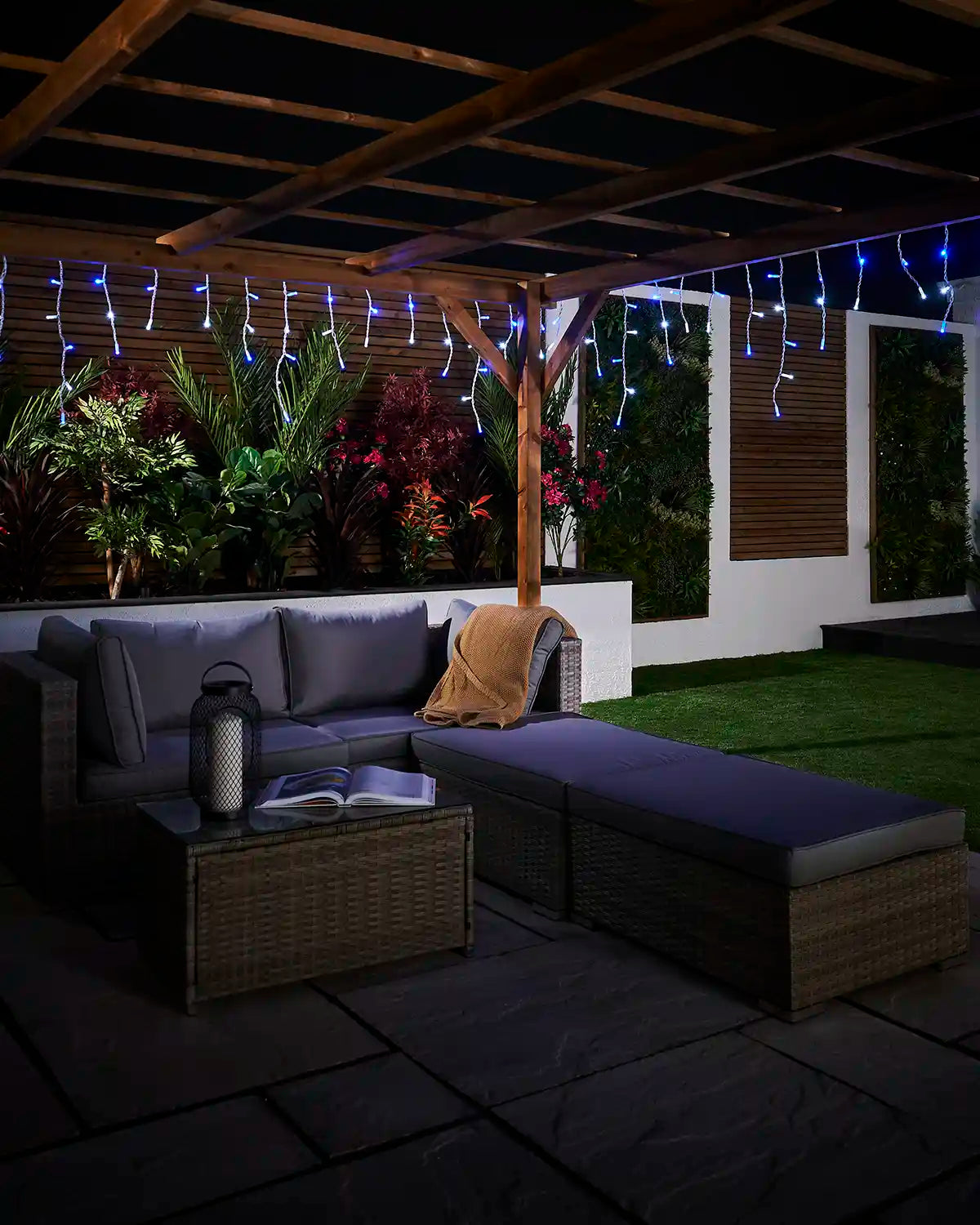 Blue and white icicle lights displayed above an outdoor seating area under a pergola.