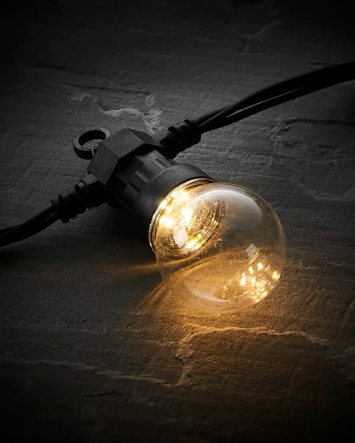 Close-up of a clear bulb warm white festoon light on a black cable.