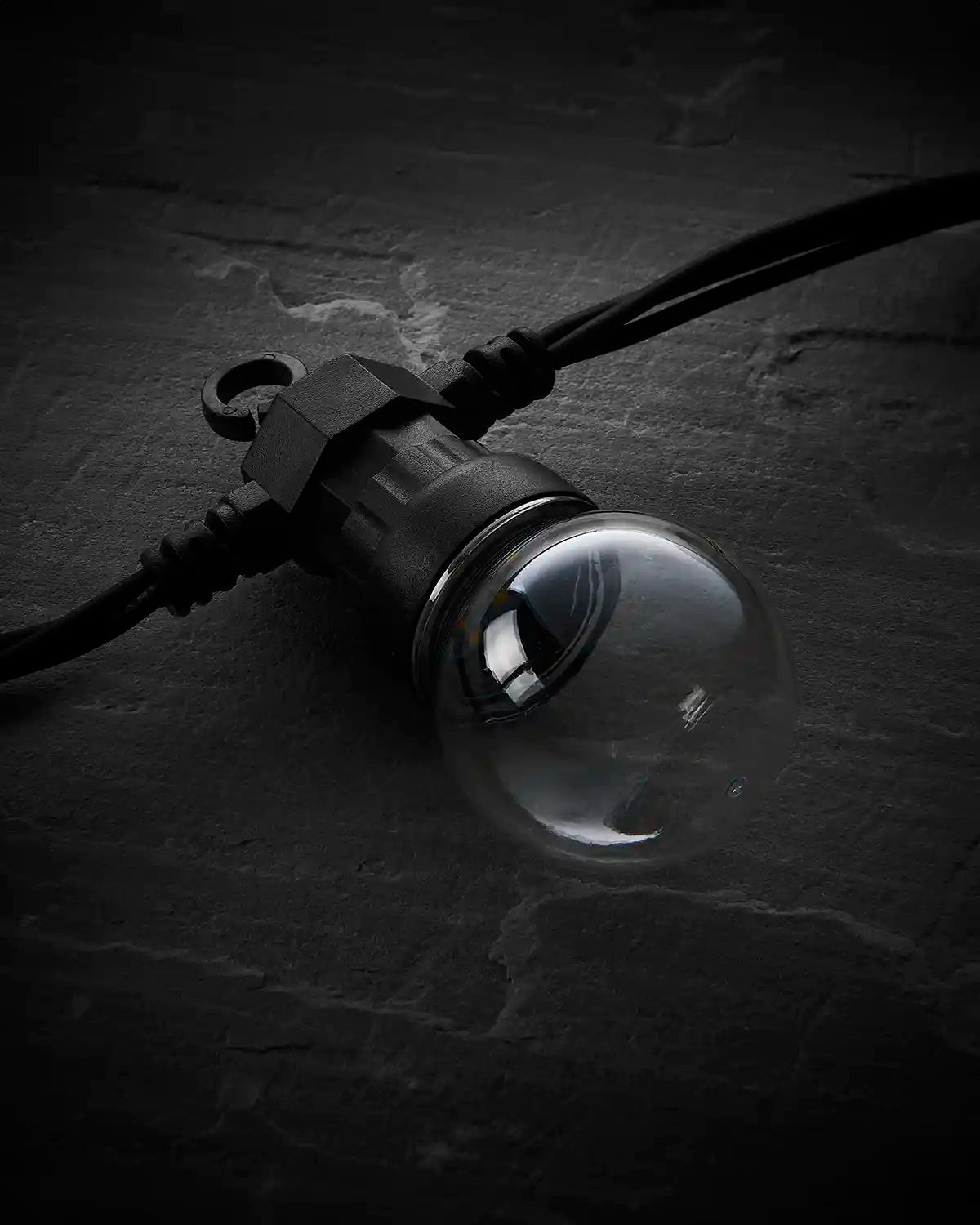 Unlit clear festoon bulb on black Pro Series cable against a dark background.