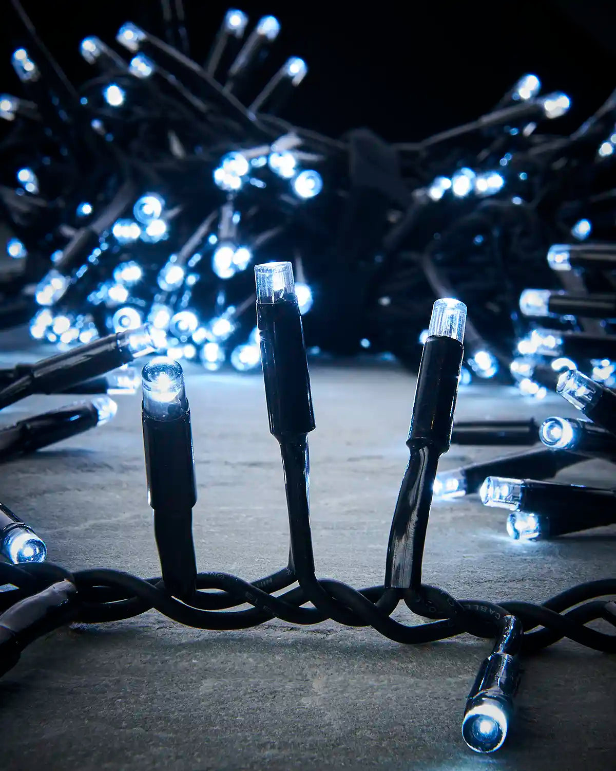 Close-up of white LED cluster lights with black cable on a dark surface.