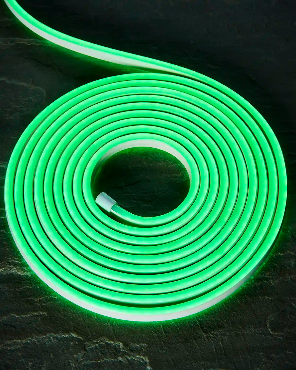 Coiled green Pro Series neon flex on a dark surface with an endcap visible.