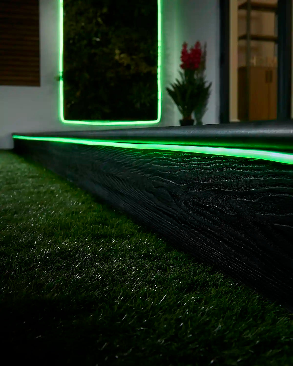 Green neon flex lighting along a garden step with a matching lit feature in the background.