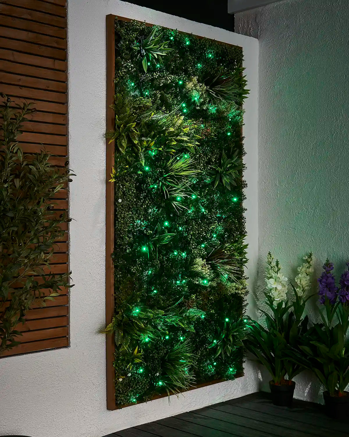 Green LED string lights arranged across a living wall garden display.