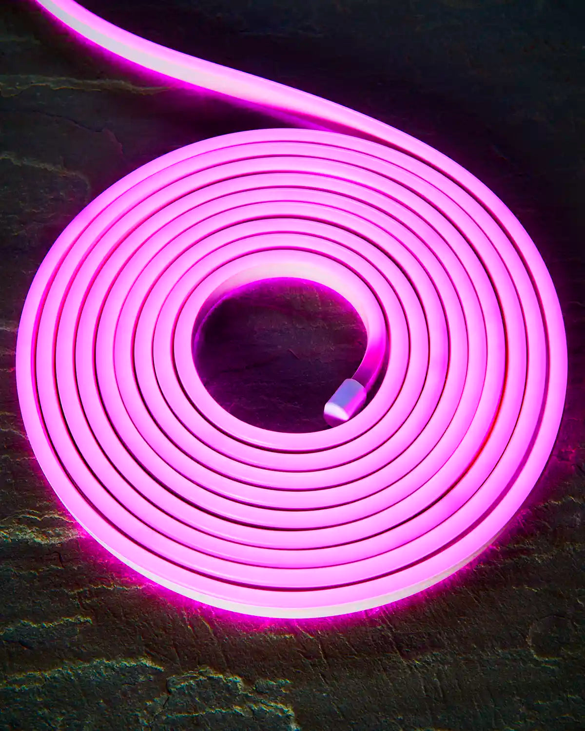 Coiled pink Pro Series Neon Flex light on a dark surface.
