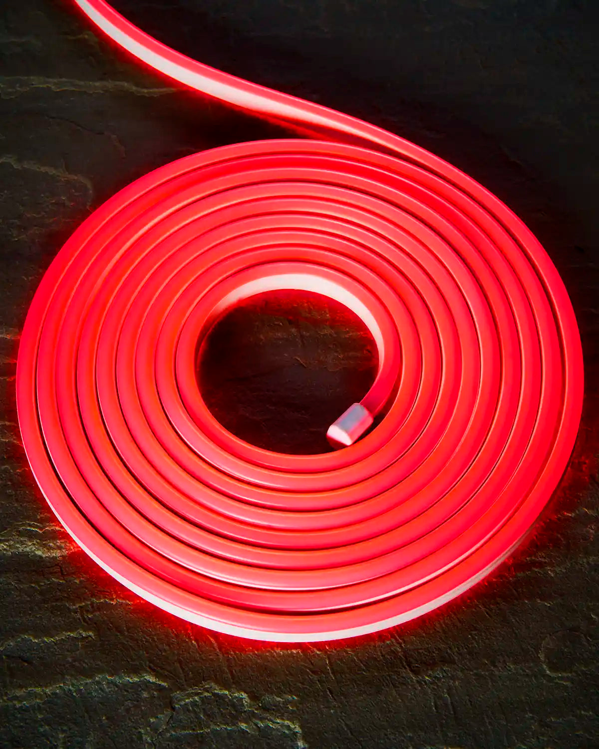 Coiled red Pro Series Neon Flex light on a dark surface.