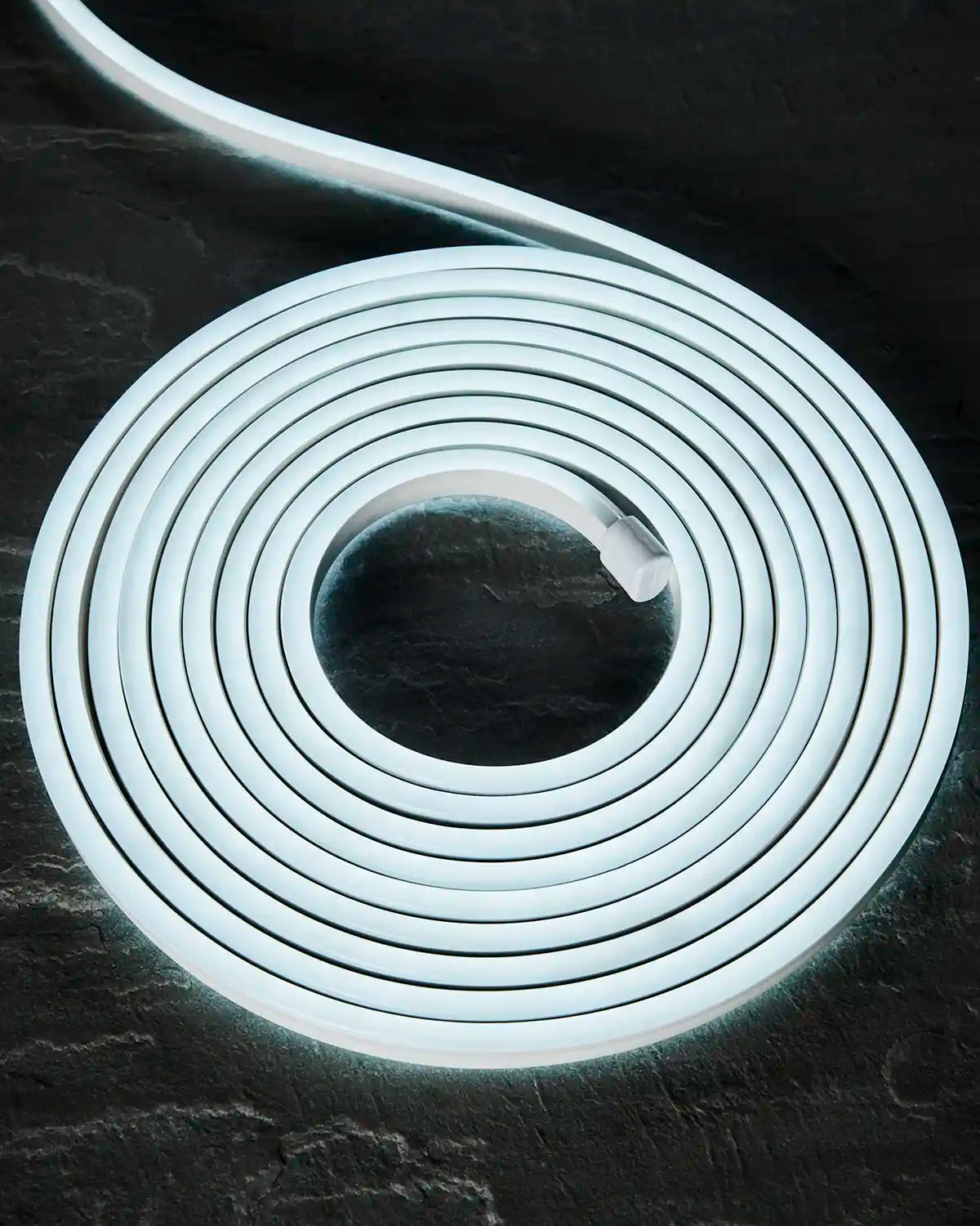 Coiled white Pro Series Neon Flex light on a dark surface.