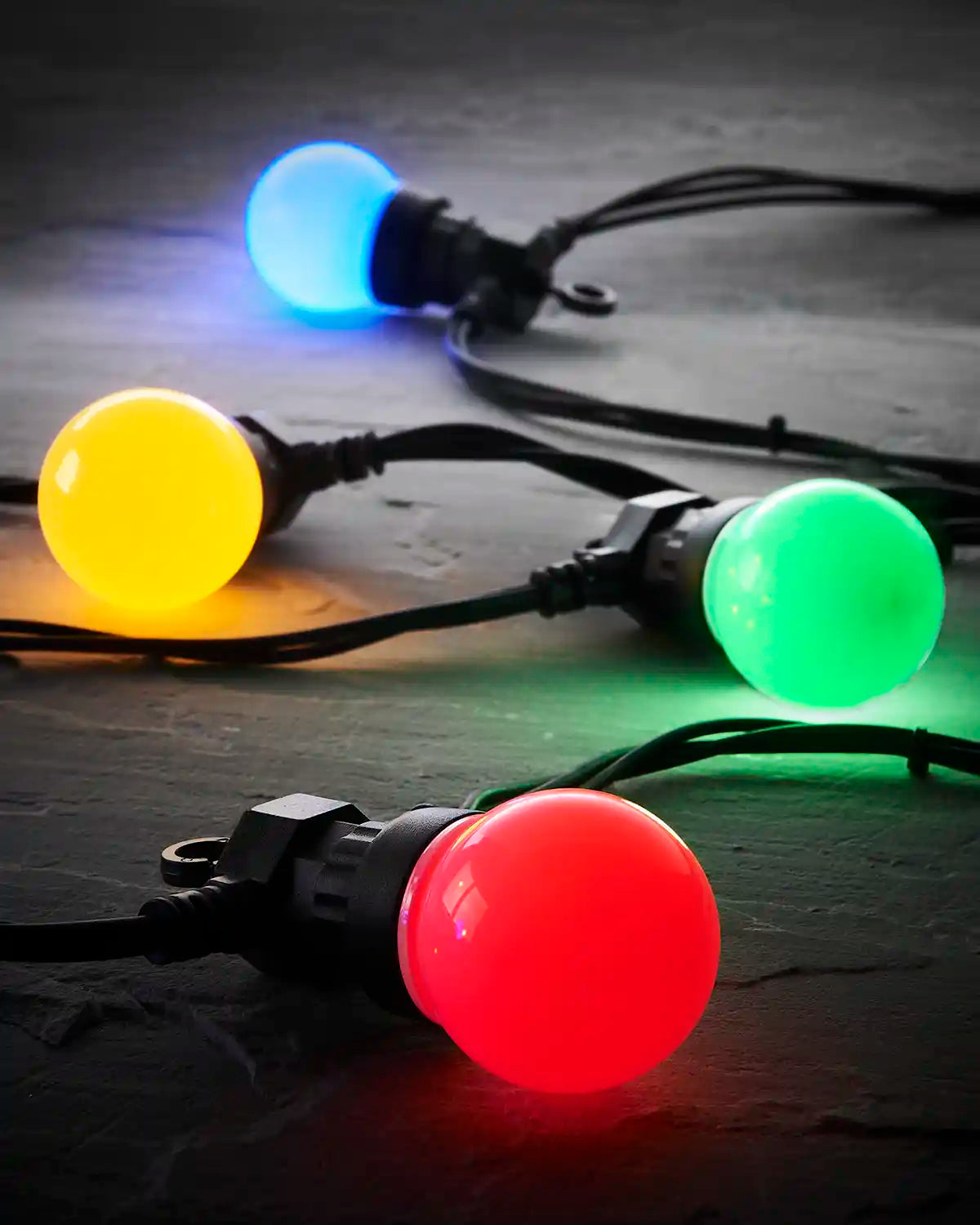 Close-up of multi colour frosted festoon bulbs on black cable.