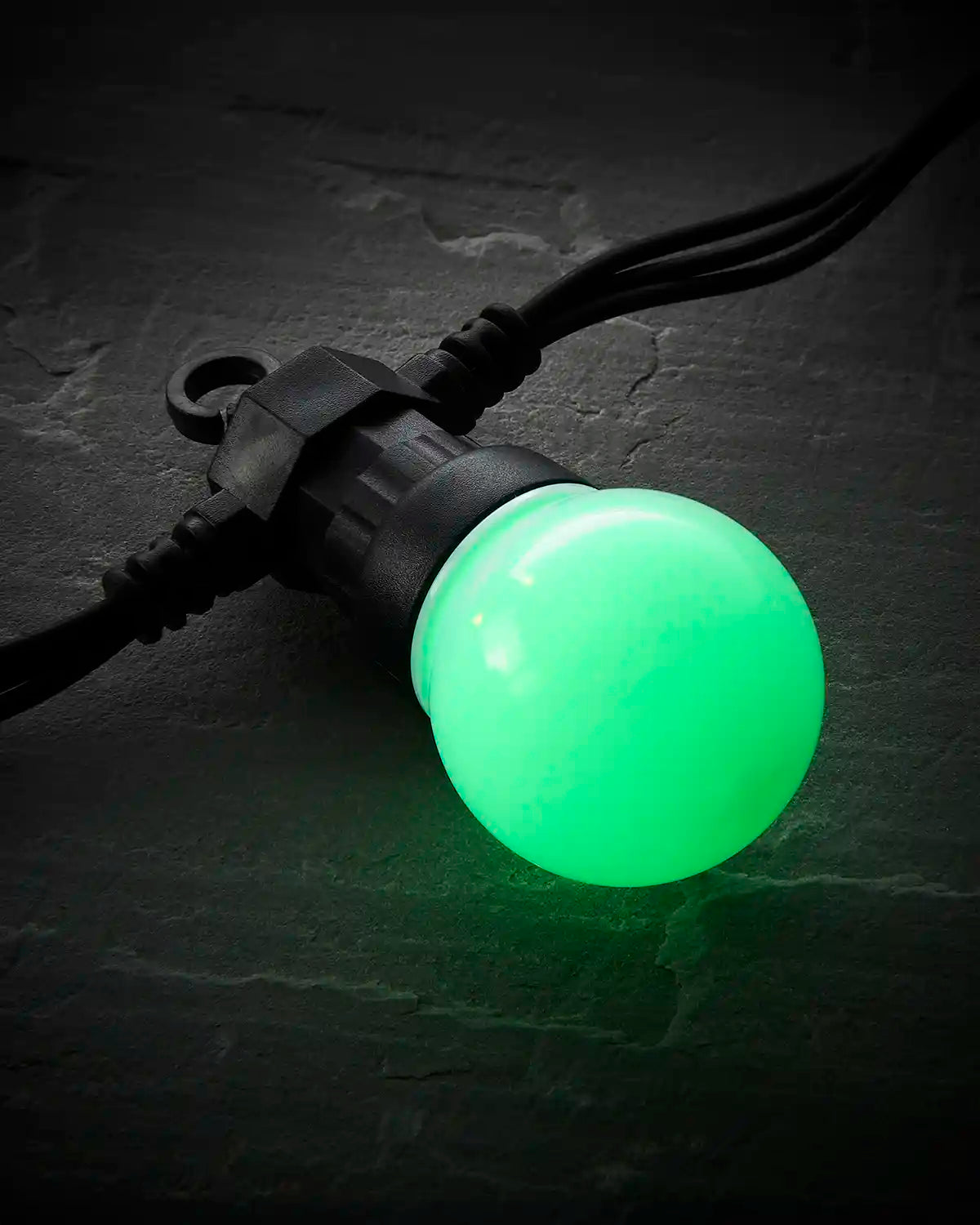 Close-up of a green frosted festoon bulb on a black Pro Series cable.
