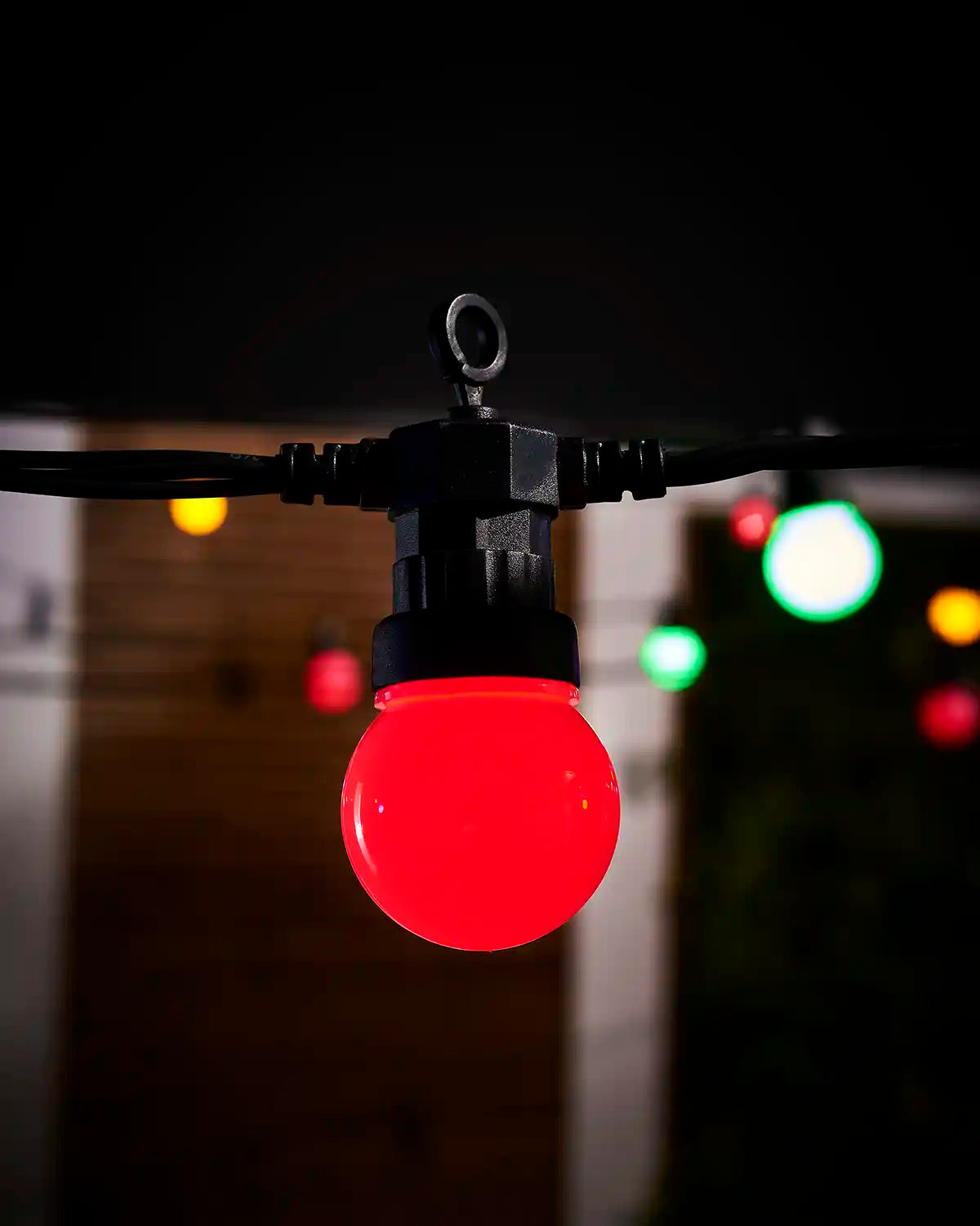 Close-up of a red frosted festoon bulb on black cable.