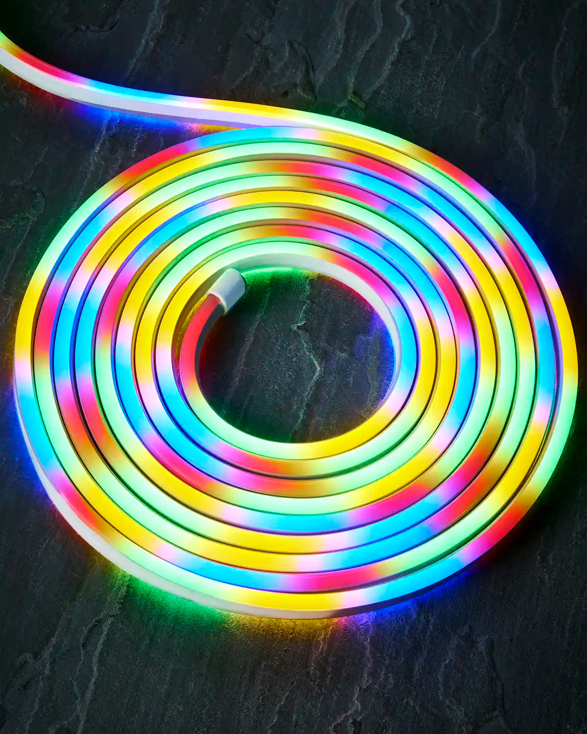 Coiled multi colour Pro Series neon flex on a dark surface with an endcap visible.