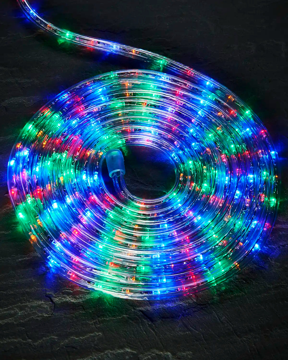 Coiled multi colour Pro Series rope light on a dark surface with an endcap visible.