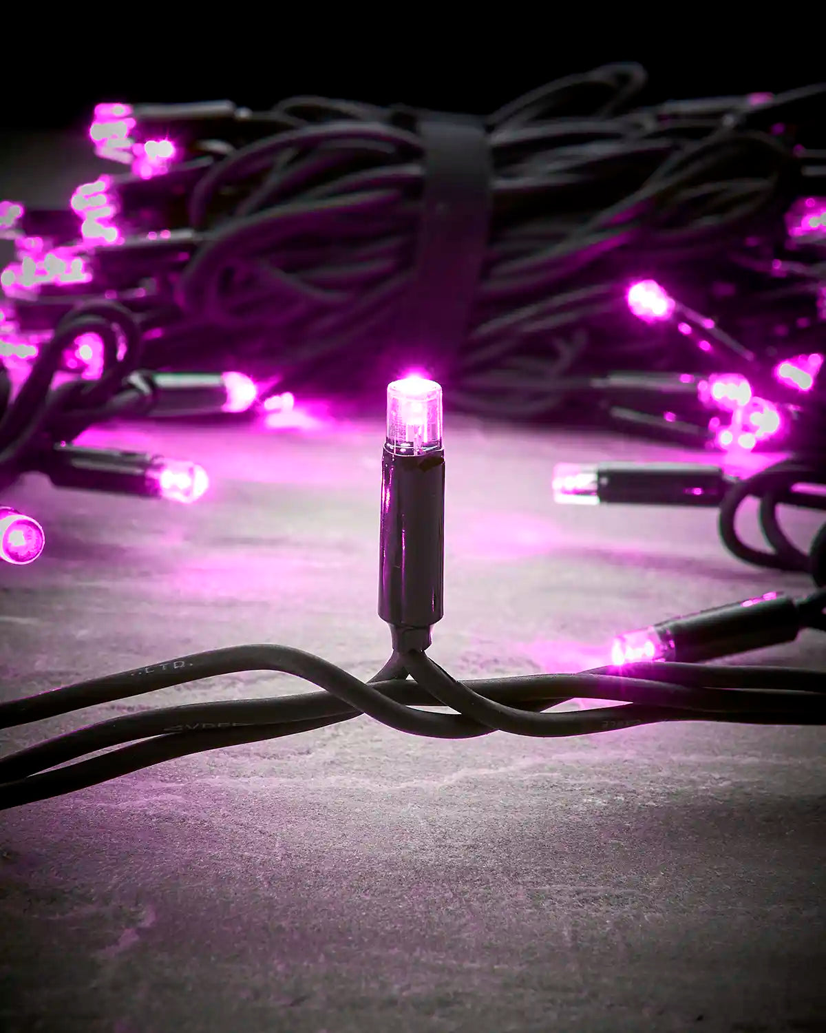 Pink Pro Series LED string lights on a black cable, shown coiled in the background.