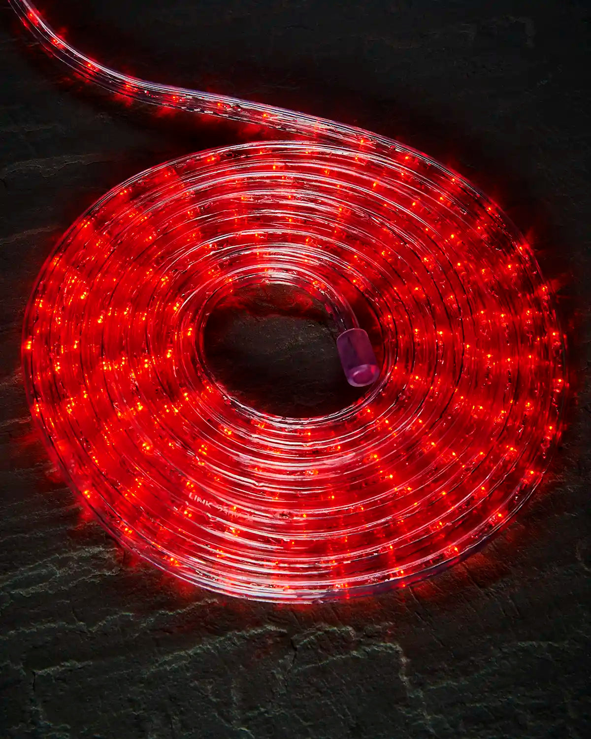 Coiled red Pro Series rope light on a dark surface with an endcap visible.