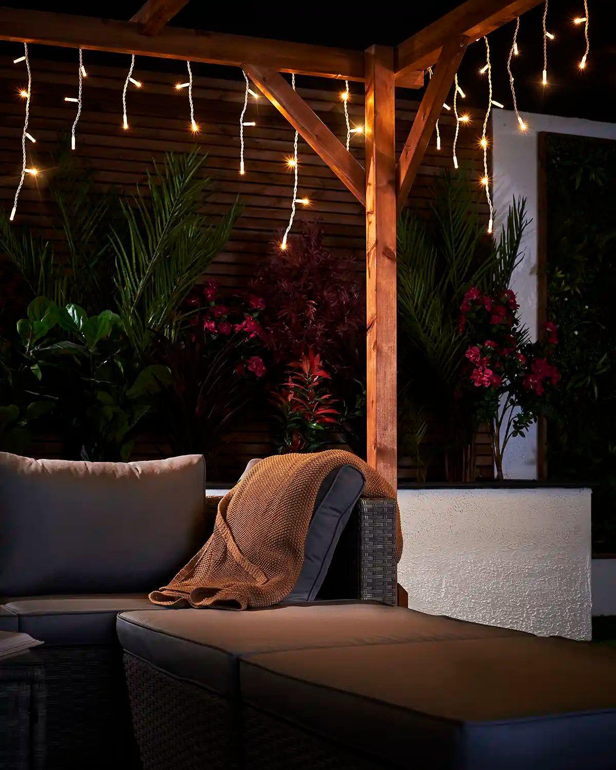 Warm white twinkling icicle lights displayed over an outdoor seating area.