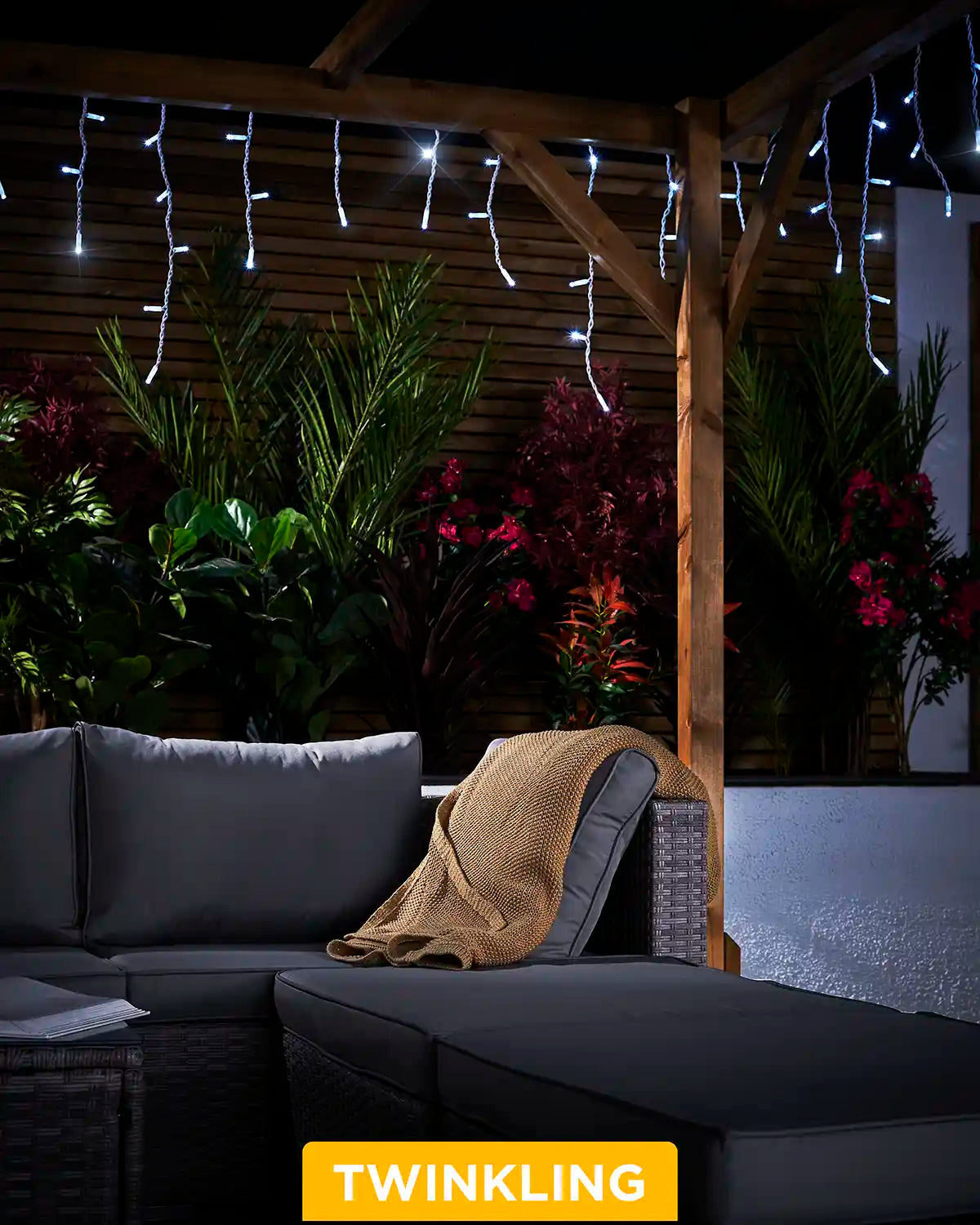 White twinkling icicle lights hanging from a wooden pergola above outdoor seating.