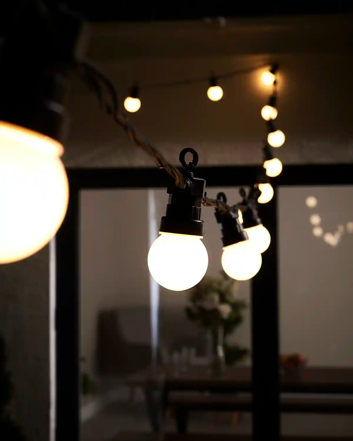 Warm white festoon lights hanging across an outdoor patio area.
