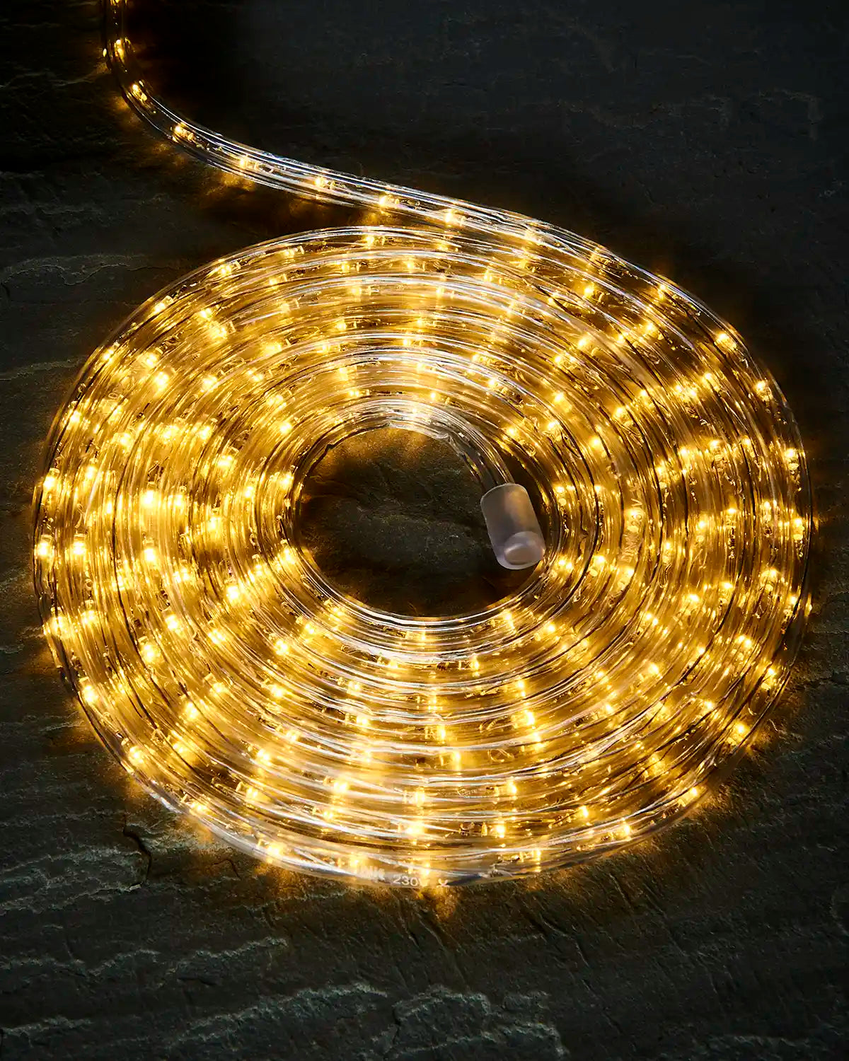 Coiled warm white Pro Series rope light on a dark surface with an endcap visible.