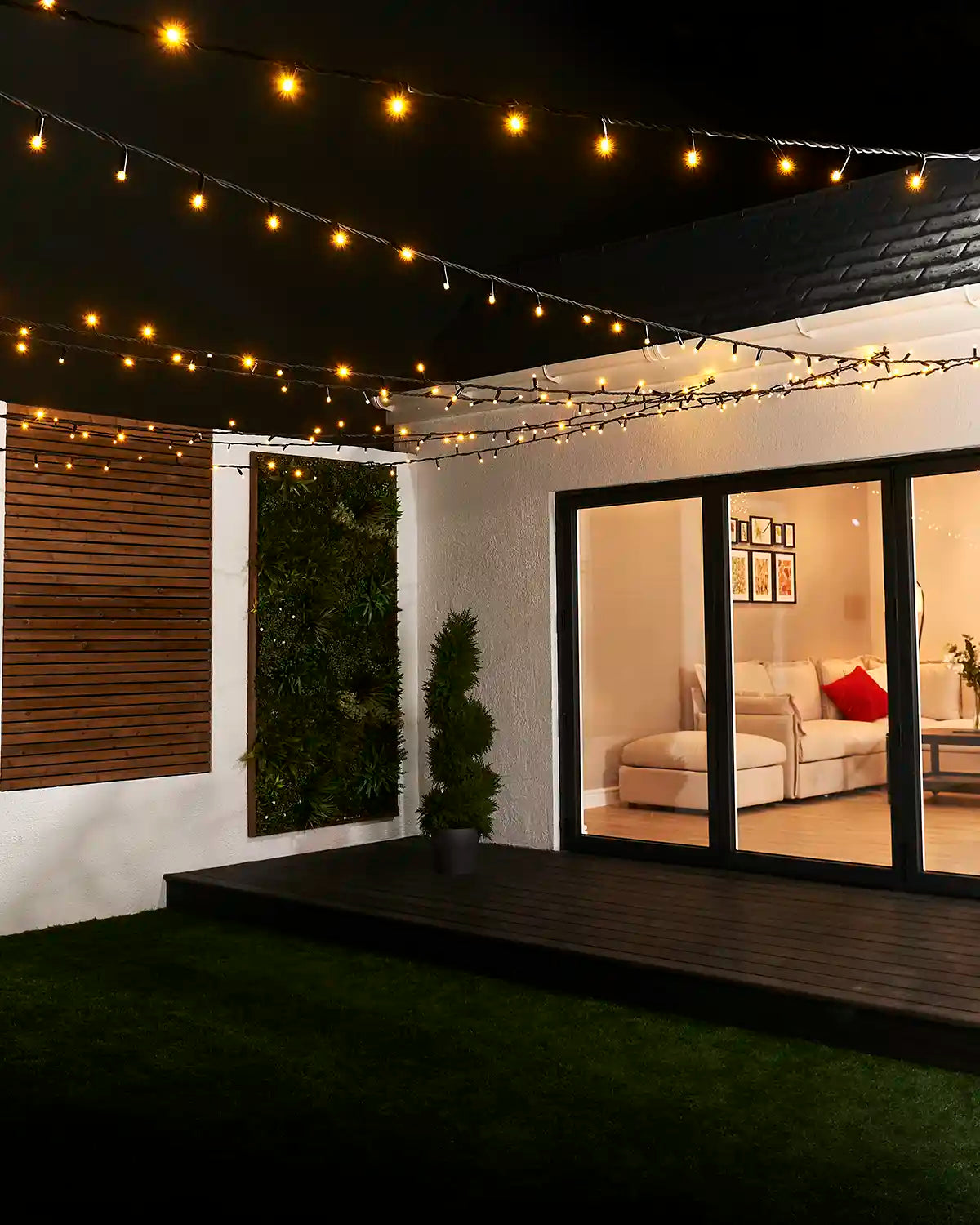 Warm white string lights with black cable suspended overhead across a garden seating area.