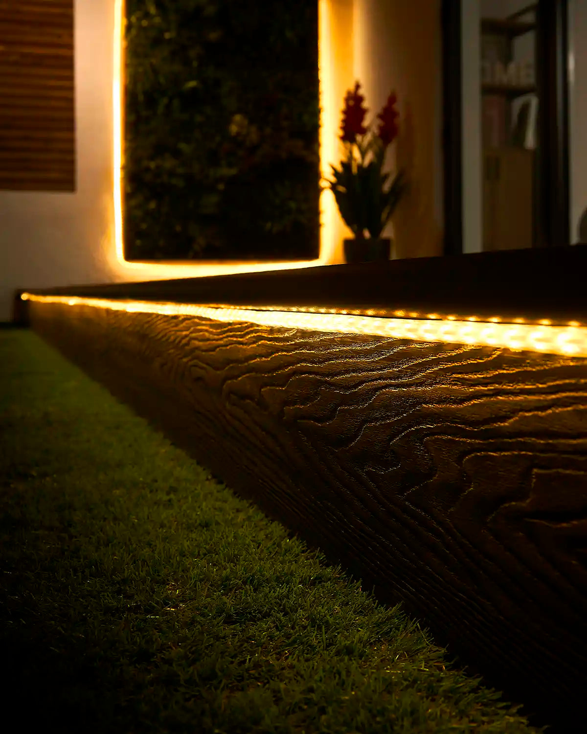 Warm white strip light running along an outdoor step with matching lighting around a garden wall feature.