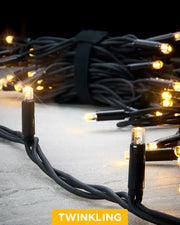 Close-up of warm white Pro Series twinkle string lights with a black cable on a grey surface.