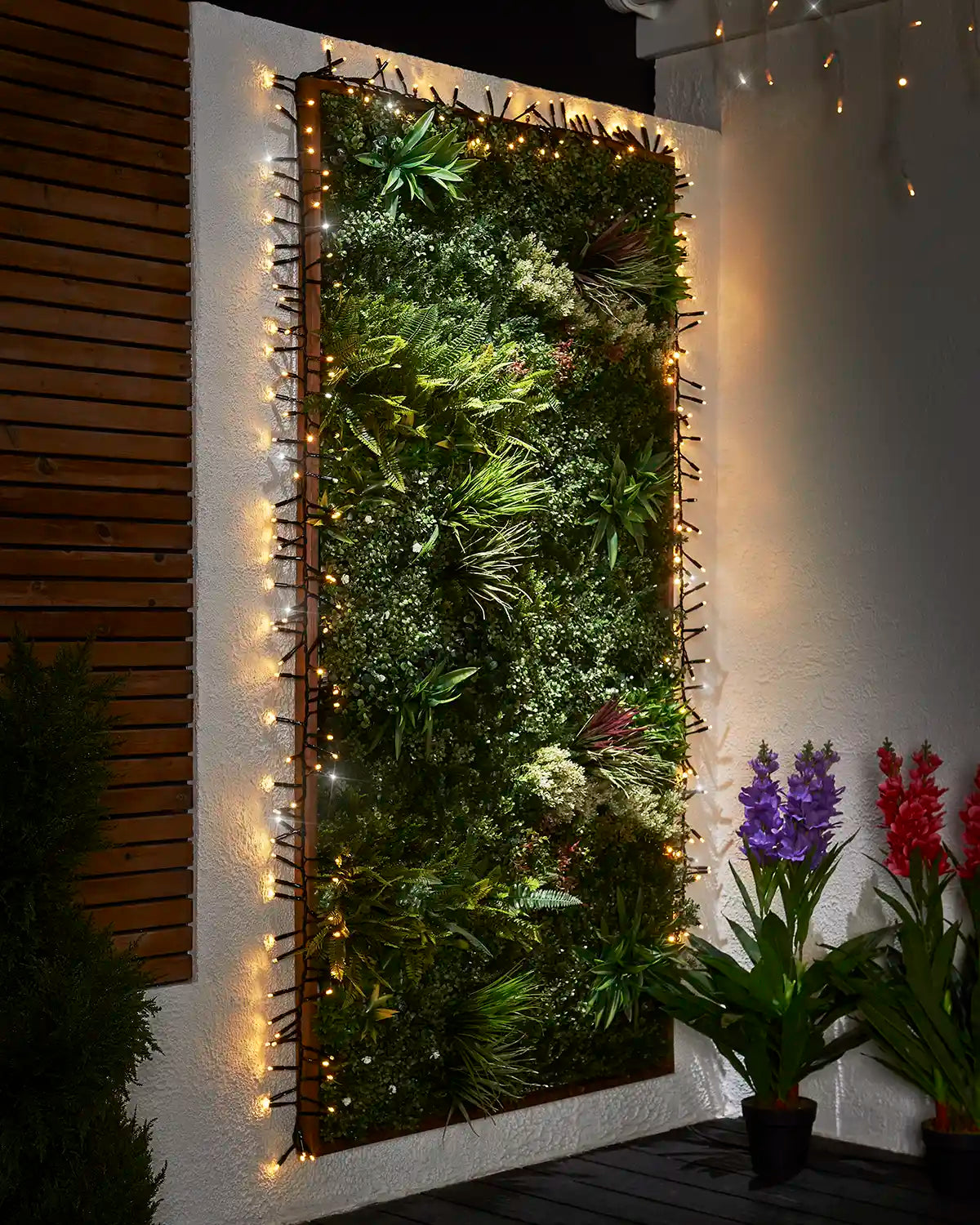 Mixed warm white and white cluster lights framing an outdoor living wall.