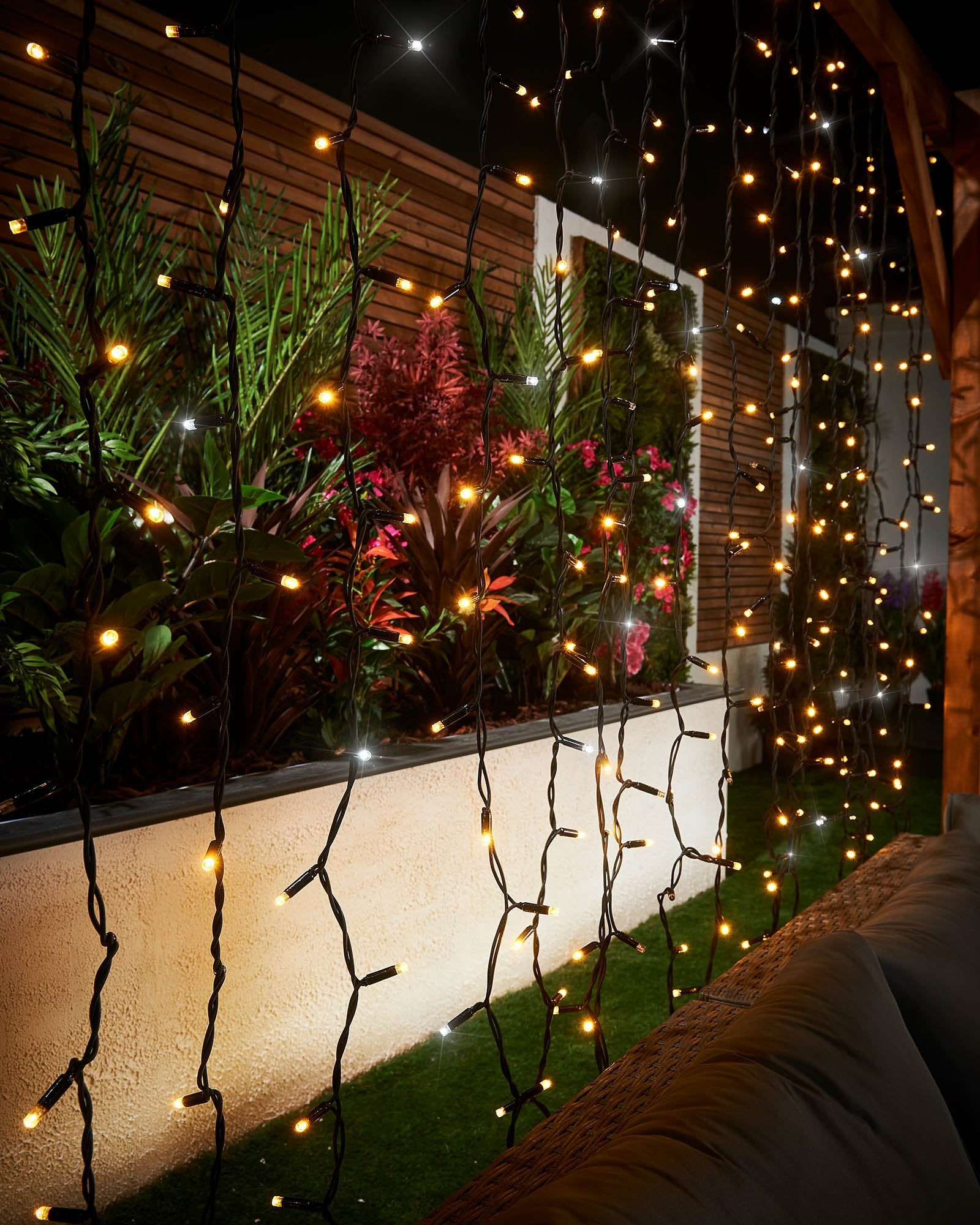 Close-up of warm white and white curtain lights hanging on black cable.