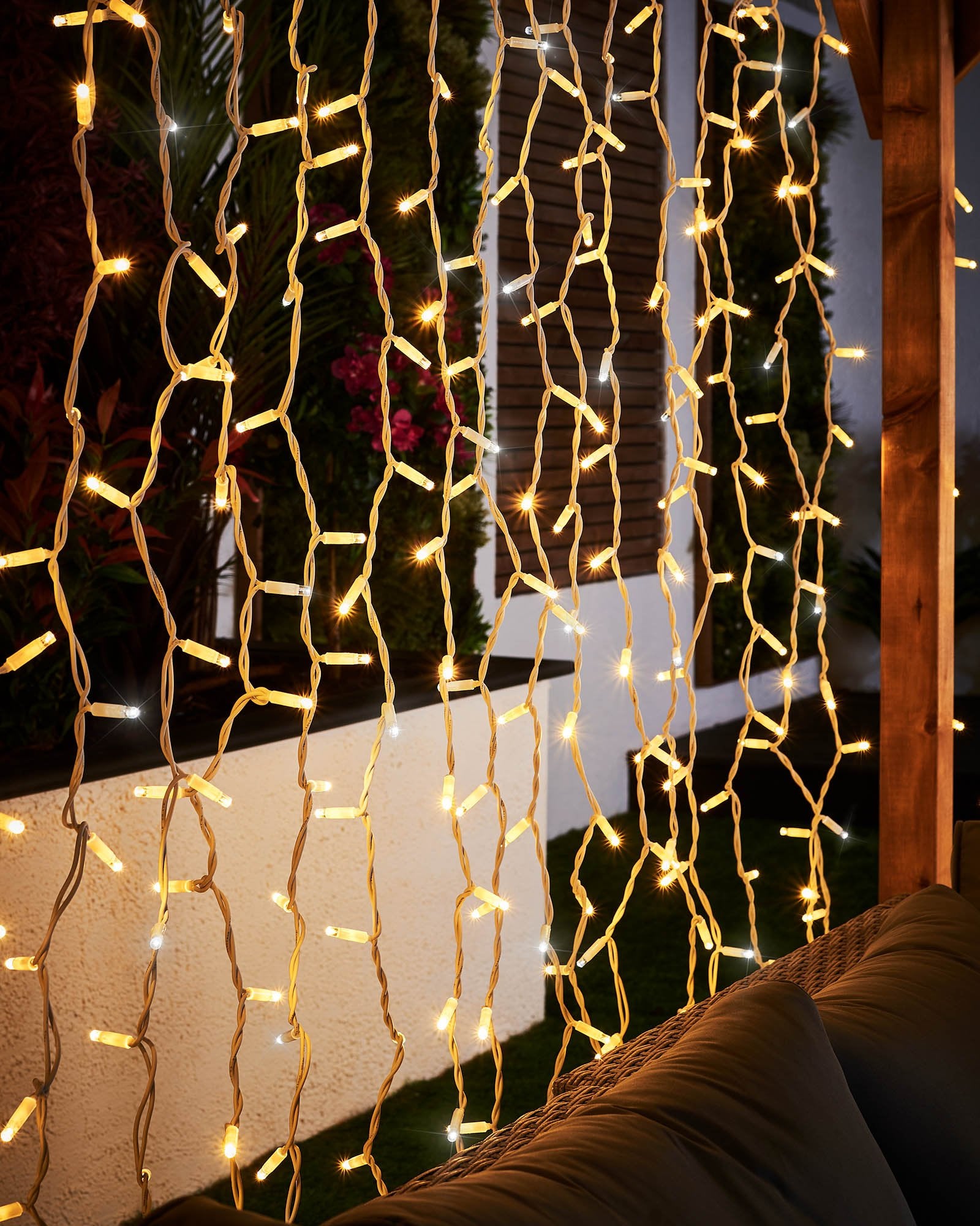 Close-up of warm white and white curtain lights hanging on white cable.