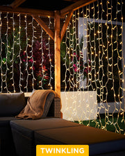 Warm white and white curtain lights with a 2.5m drop displayed around an outdoor patio seating area.
