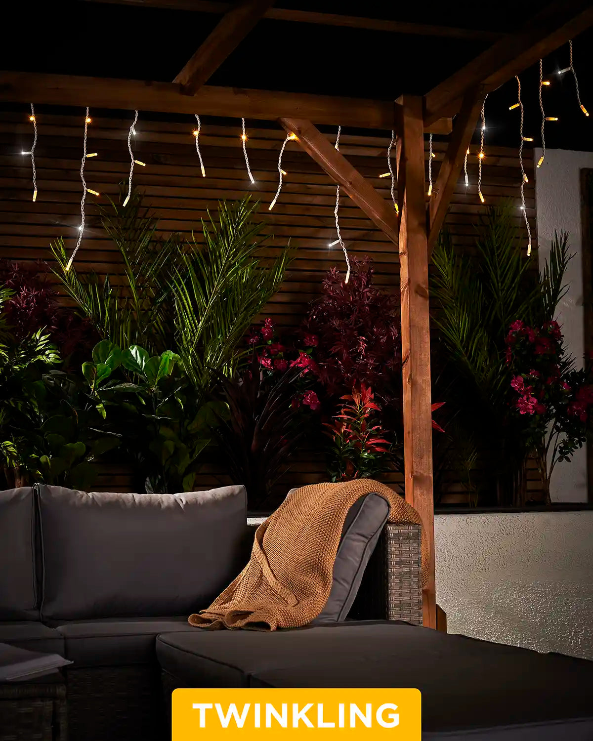 Twinkling warm white and white icicle lights hanging from a pergola above outdoor seating.