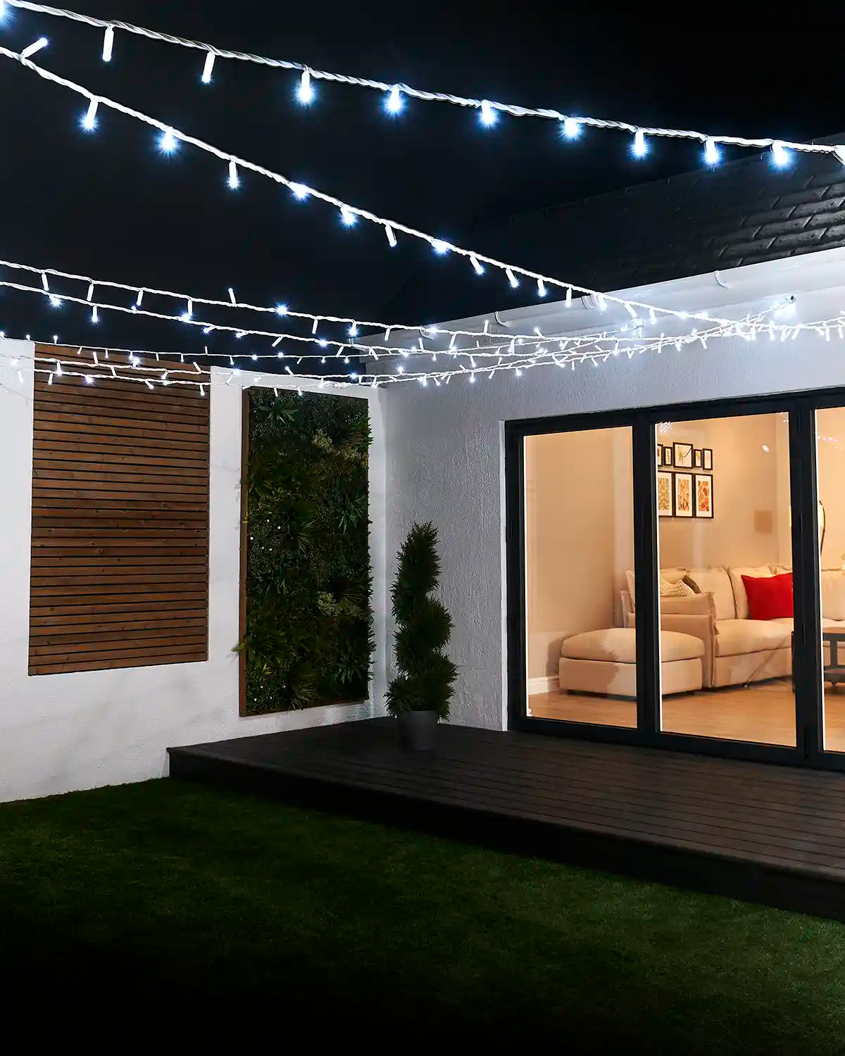 White LED string lights suspended across an outdoor garden seating area.