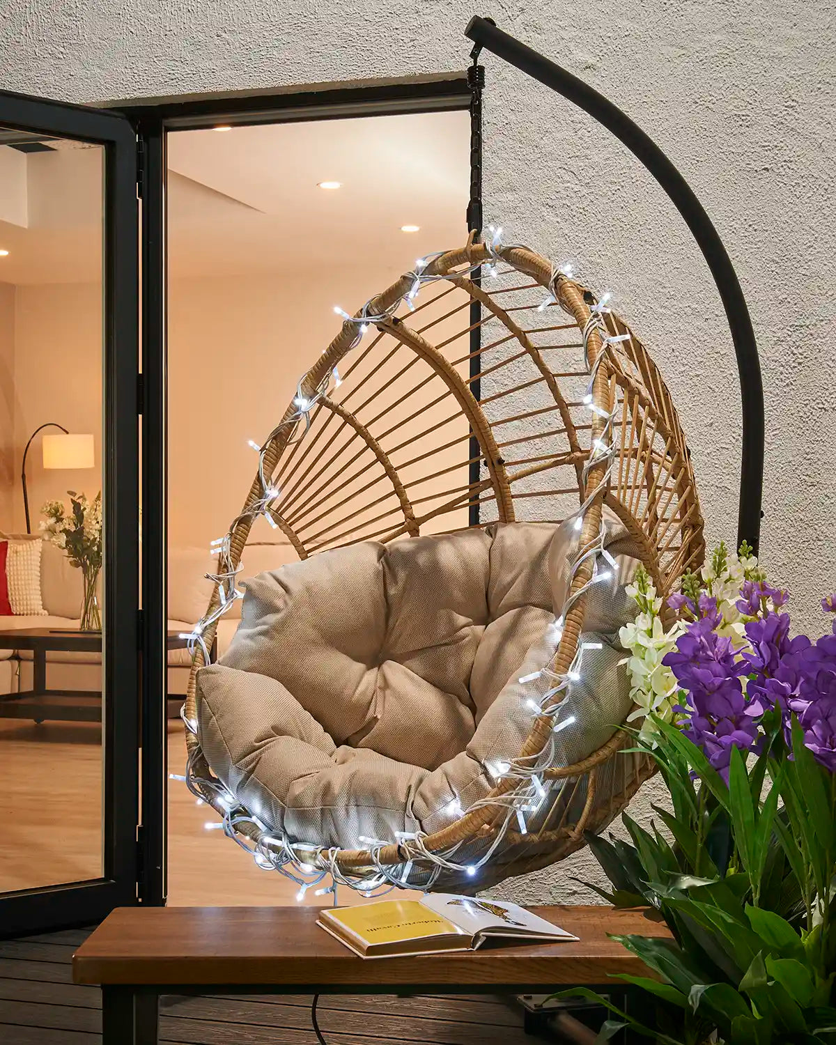 White LED string lights wrapped around a hanging garden chair.