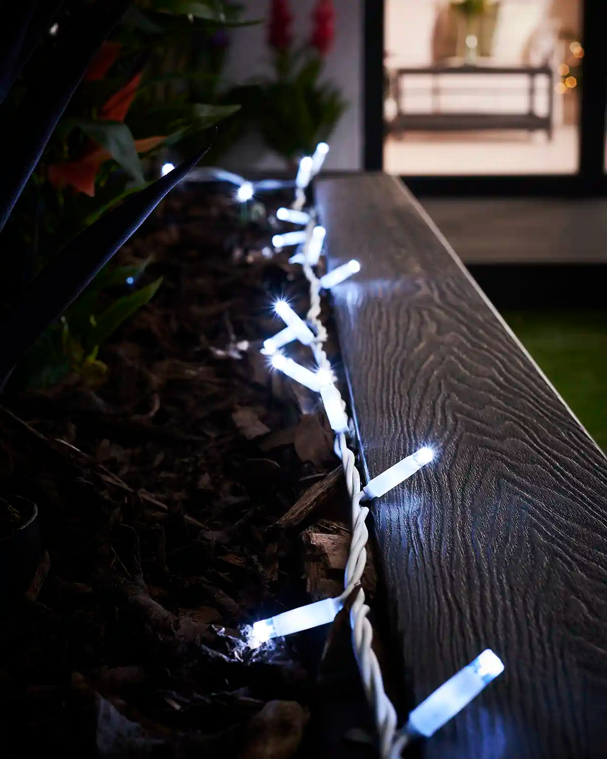 White LED string lights displayed along the edge of an outdoor planter.