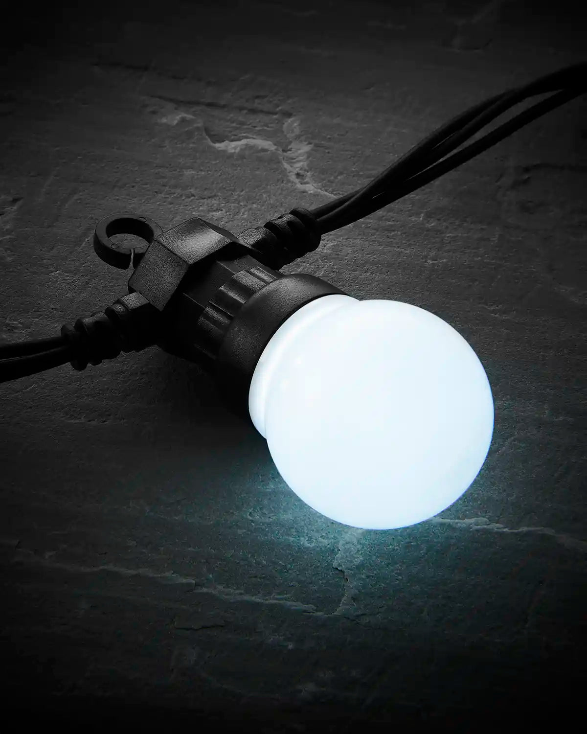 Close-up of a white frosted festoon bulb on black cable.