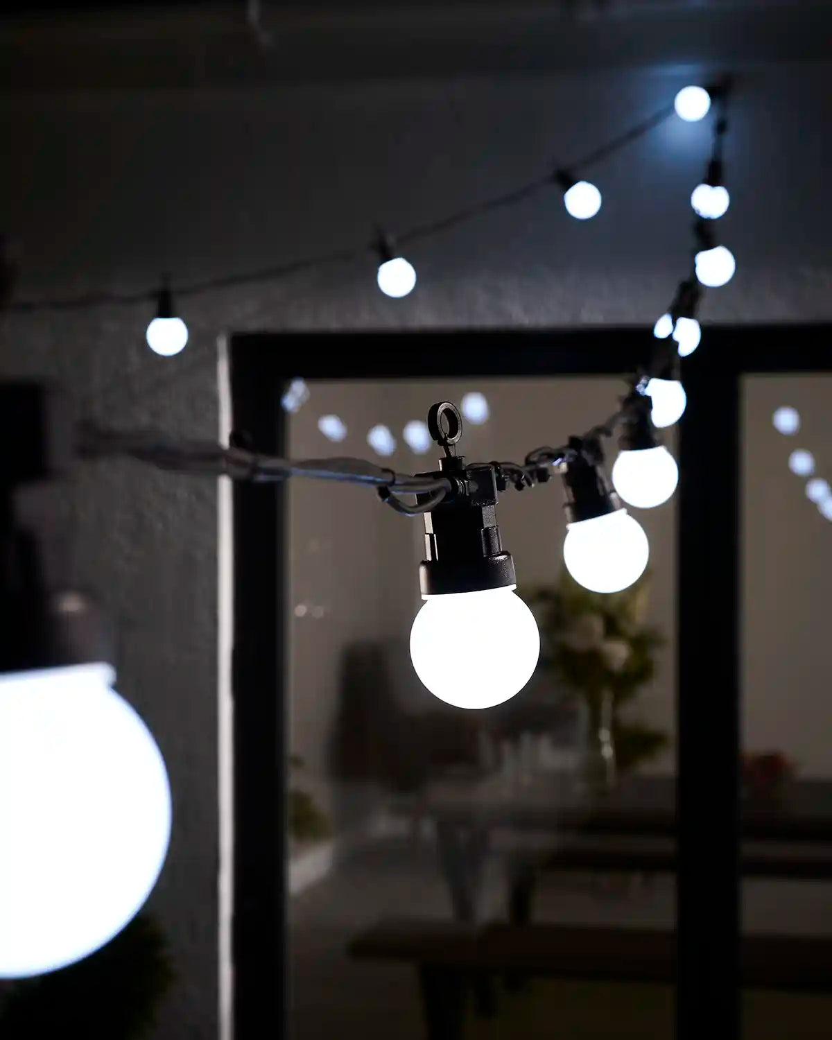 White festoon lights hanging across an outdoor patio area.