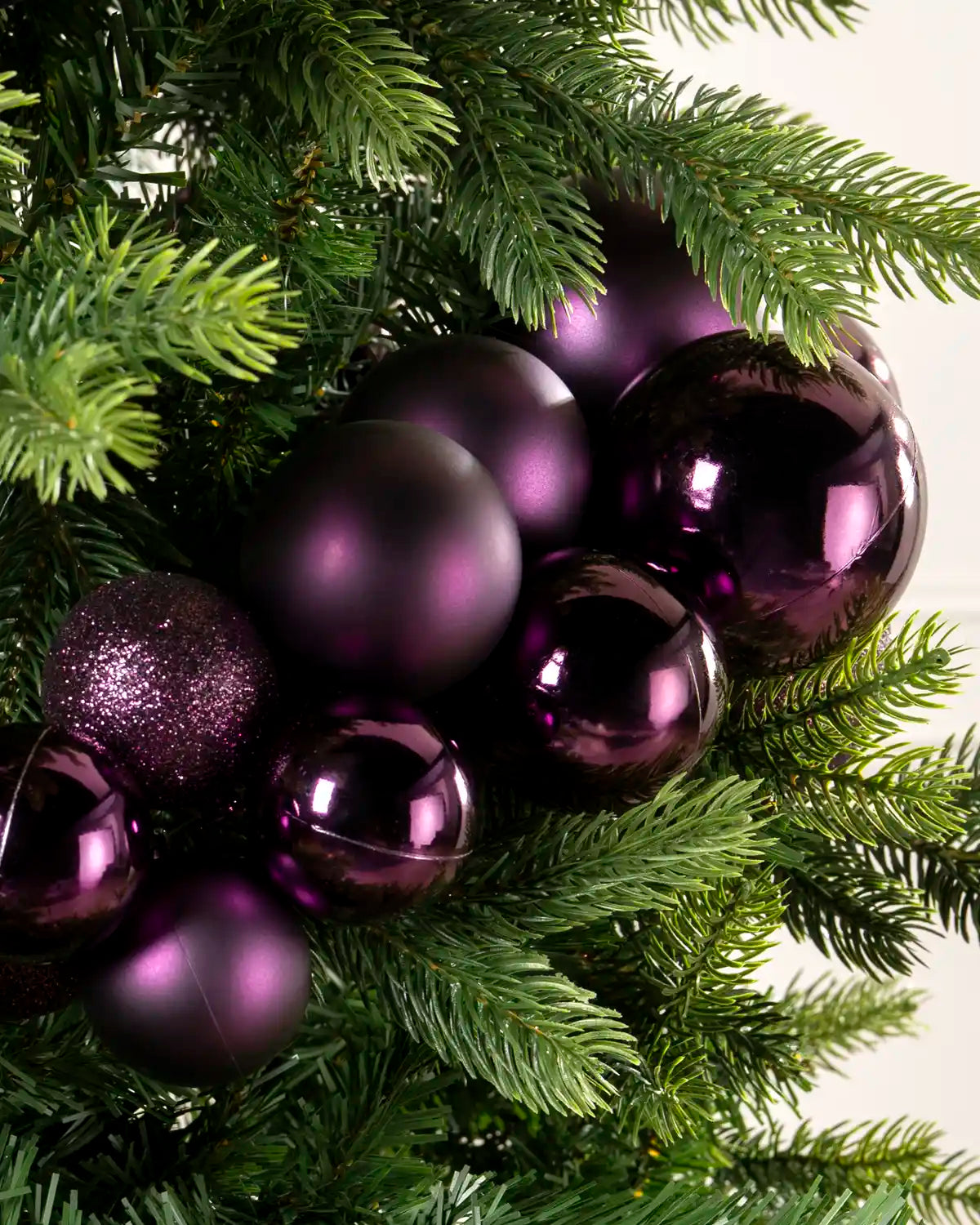 Close-up of purple baubles showing shiny, matt and glitter finishes on a Christmas tree.