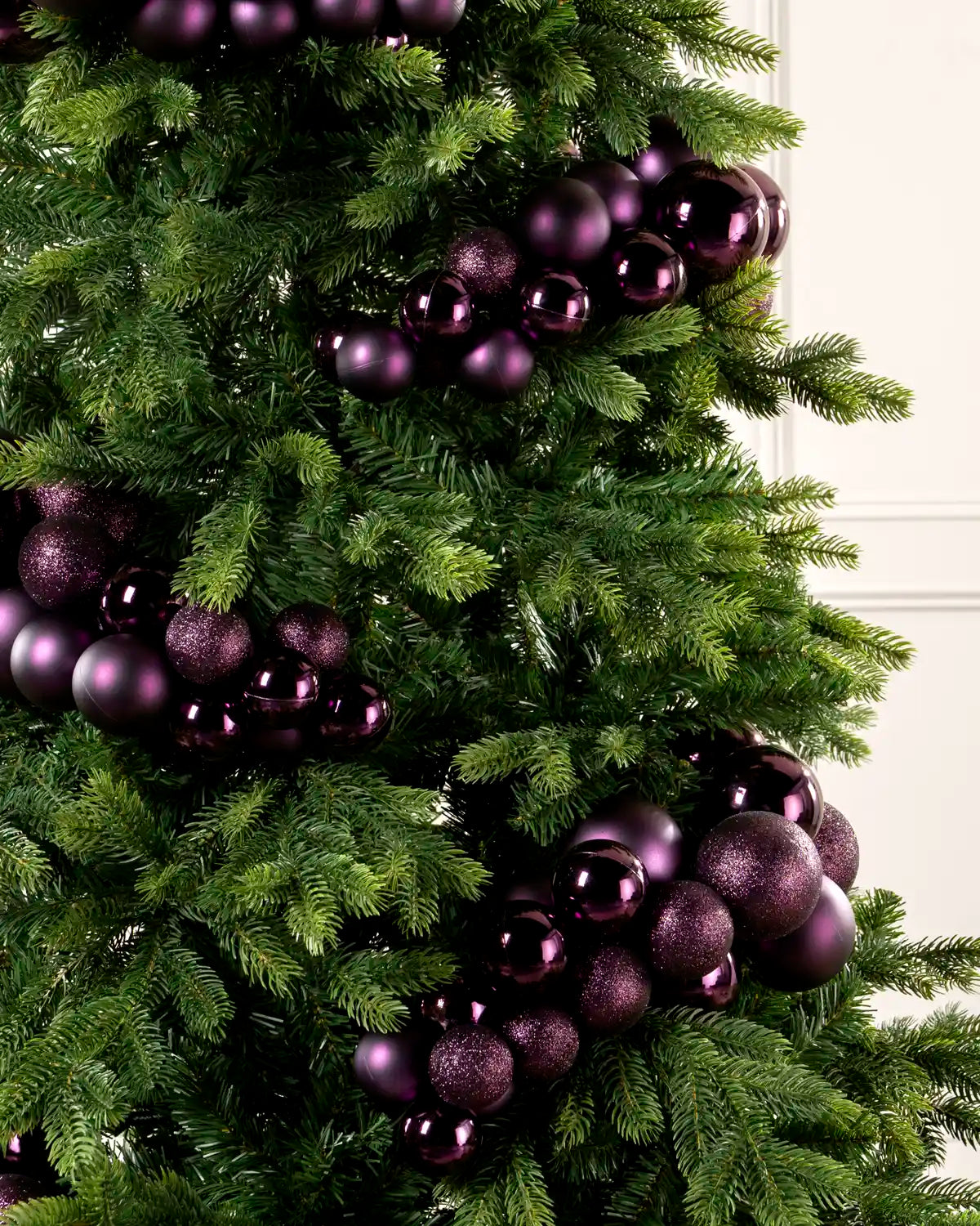 Close-up of purple bauble cluster arch on a Christmas tree showing mixed sizes and finishes.