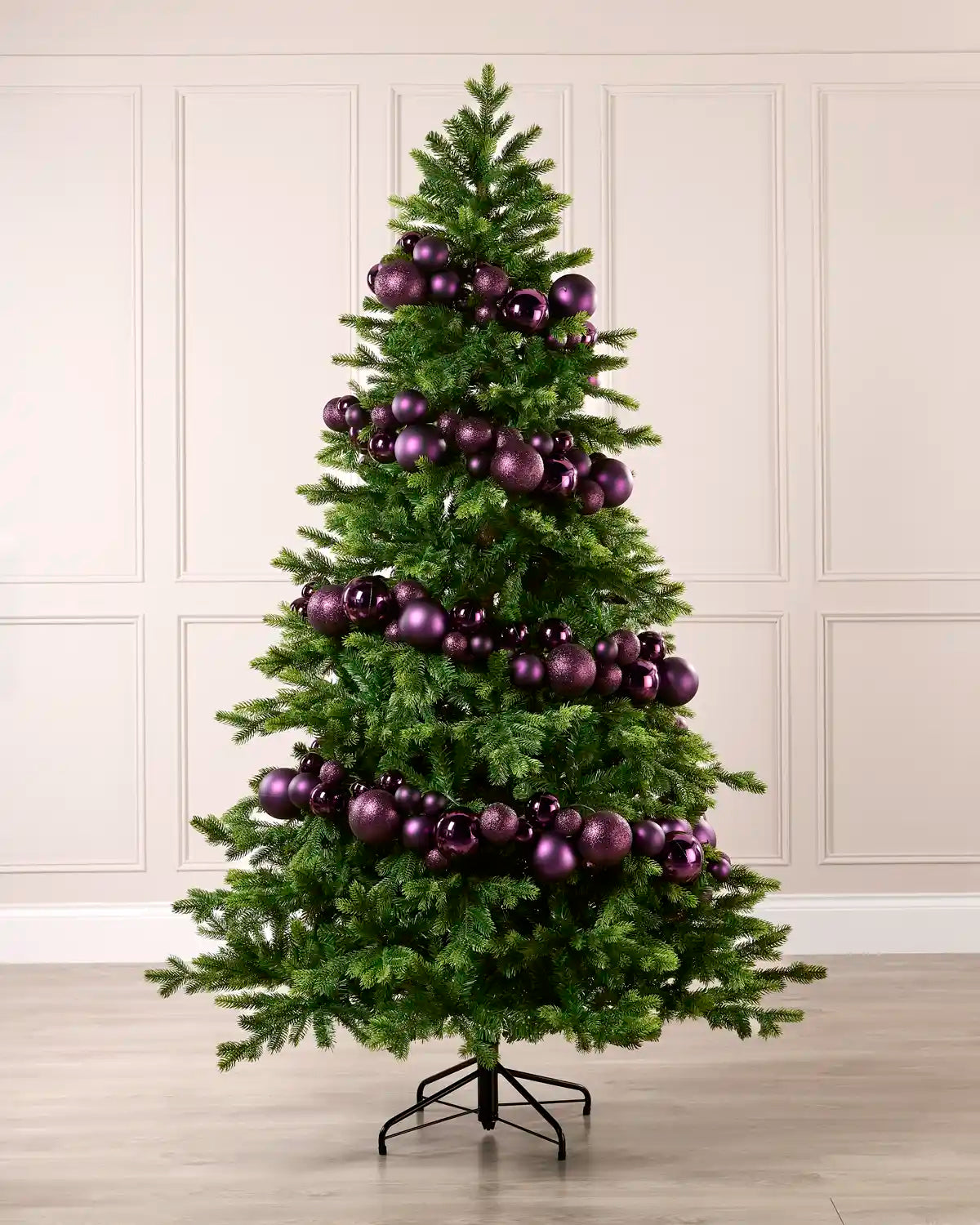 Purple bauble garland wrapped around a green Christmas tree with shiny, matt and glitter baubles.