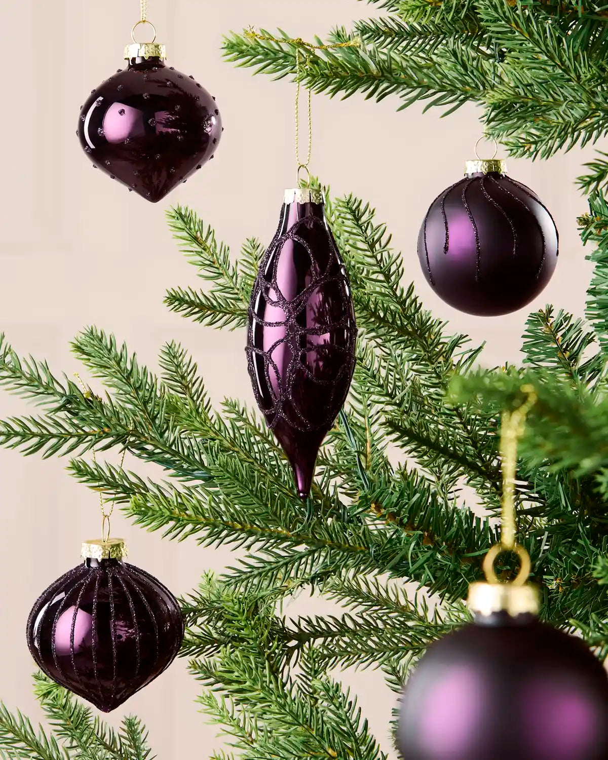 Mixed purple glass baubles with matt, shiny and glitter finishes on a Christmas tree.