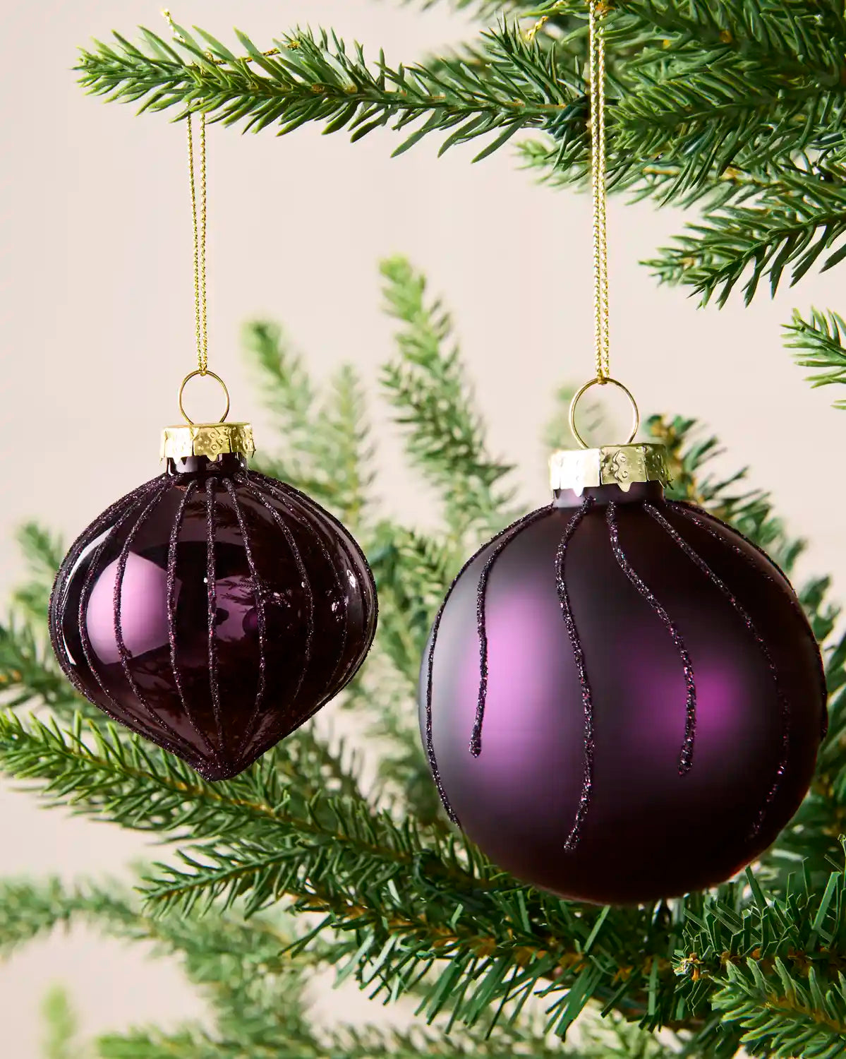 Close-up of purple onion-shaped and round glass baubles with glitter stripe patterns.