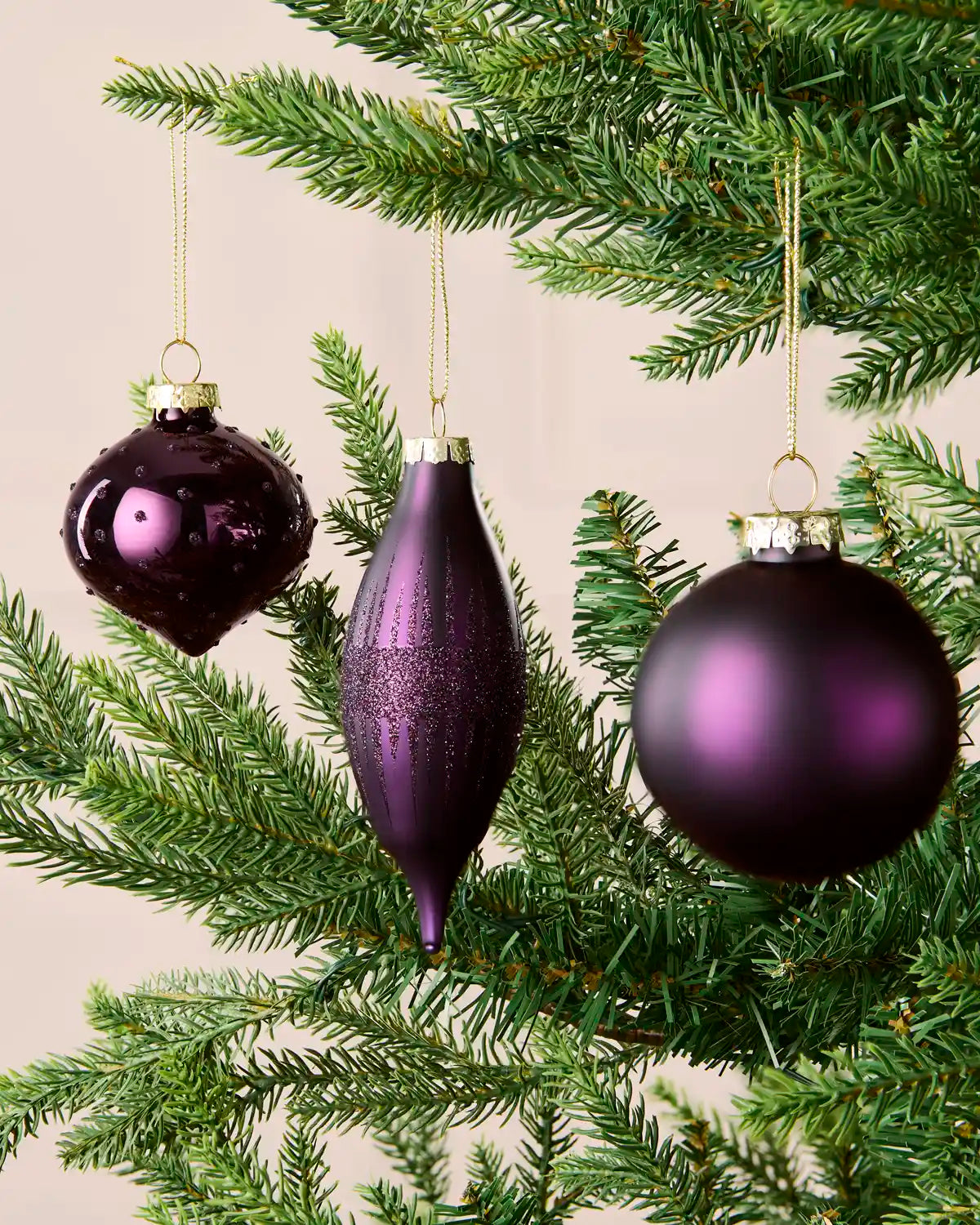 Purple round, onion-shaped and teardrop glass baubles displayed on a Christmas tree.