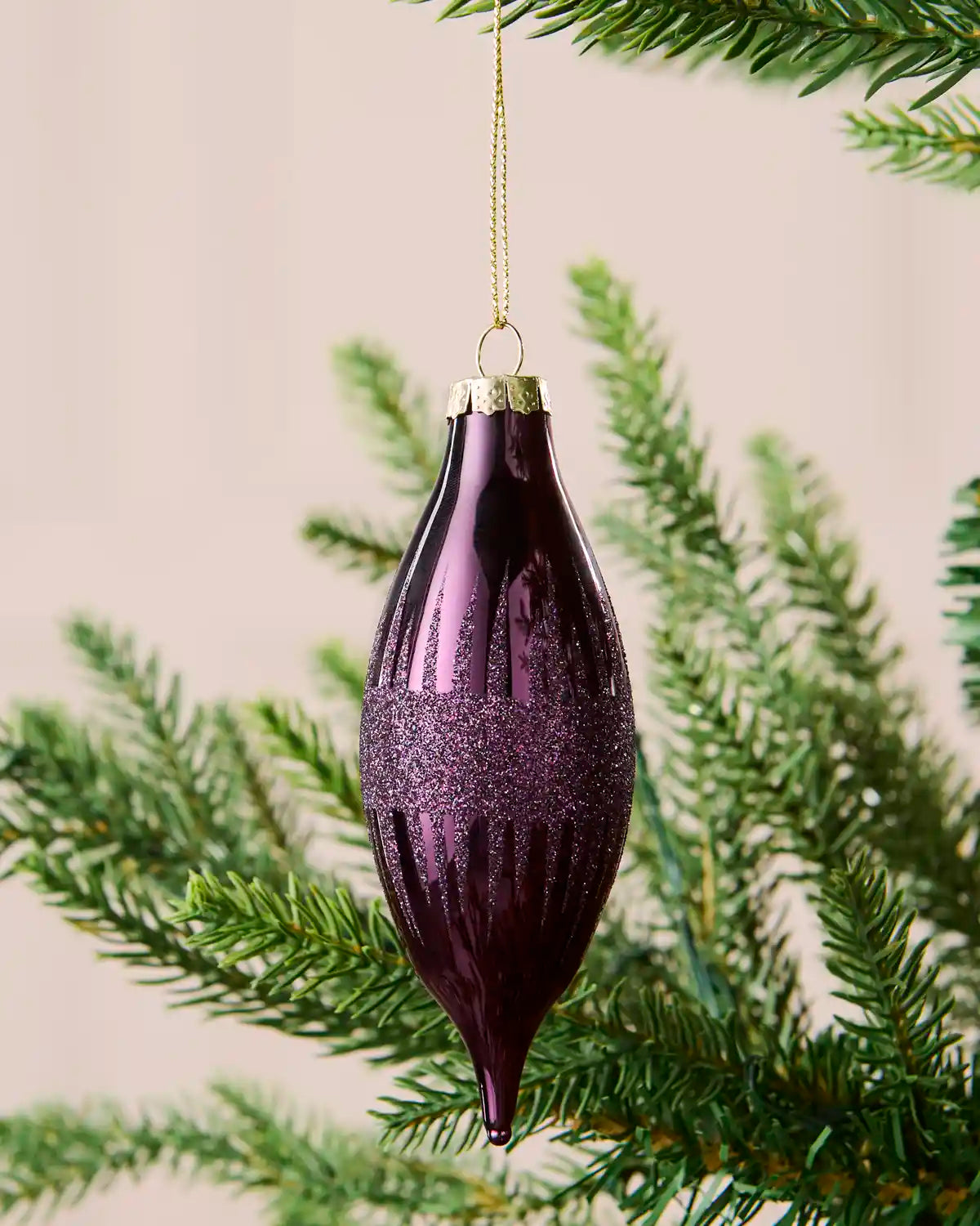 Close-up of a purple teardrop glass bauble with glitter lines and a central glitter band.